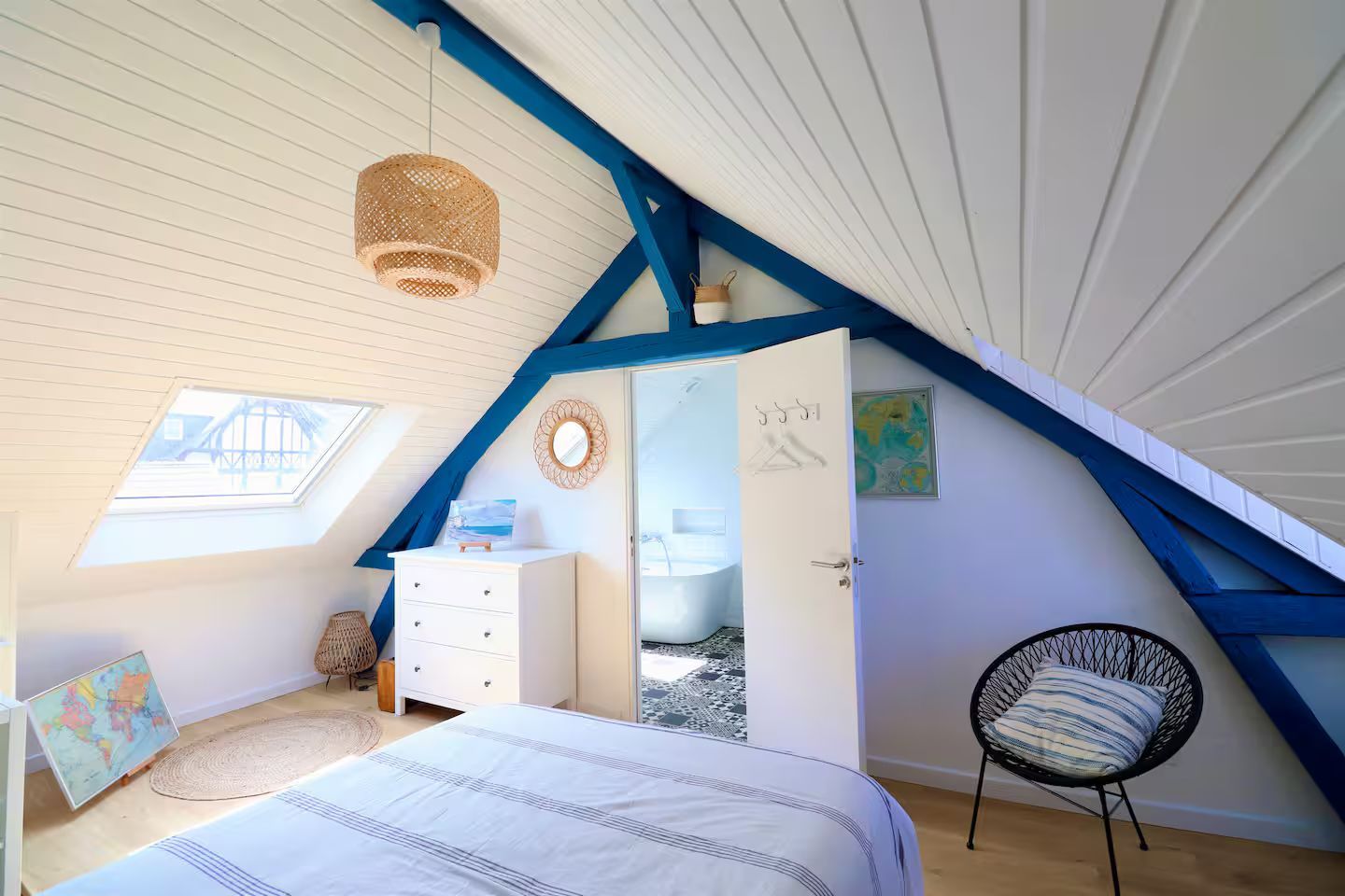 Une chambre avec un lit, une chaise et une commode dans un grenier.