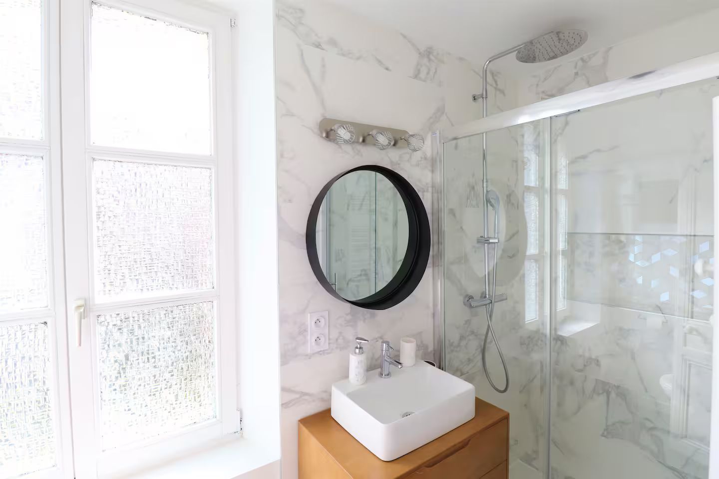 Une salle de bain avec lavabo, miroir et douche.