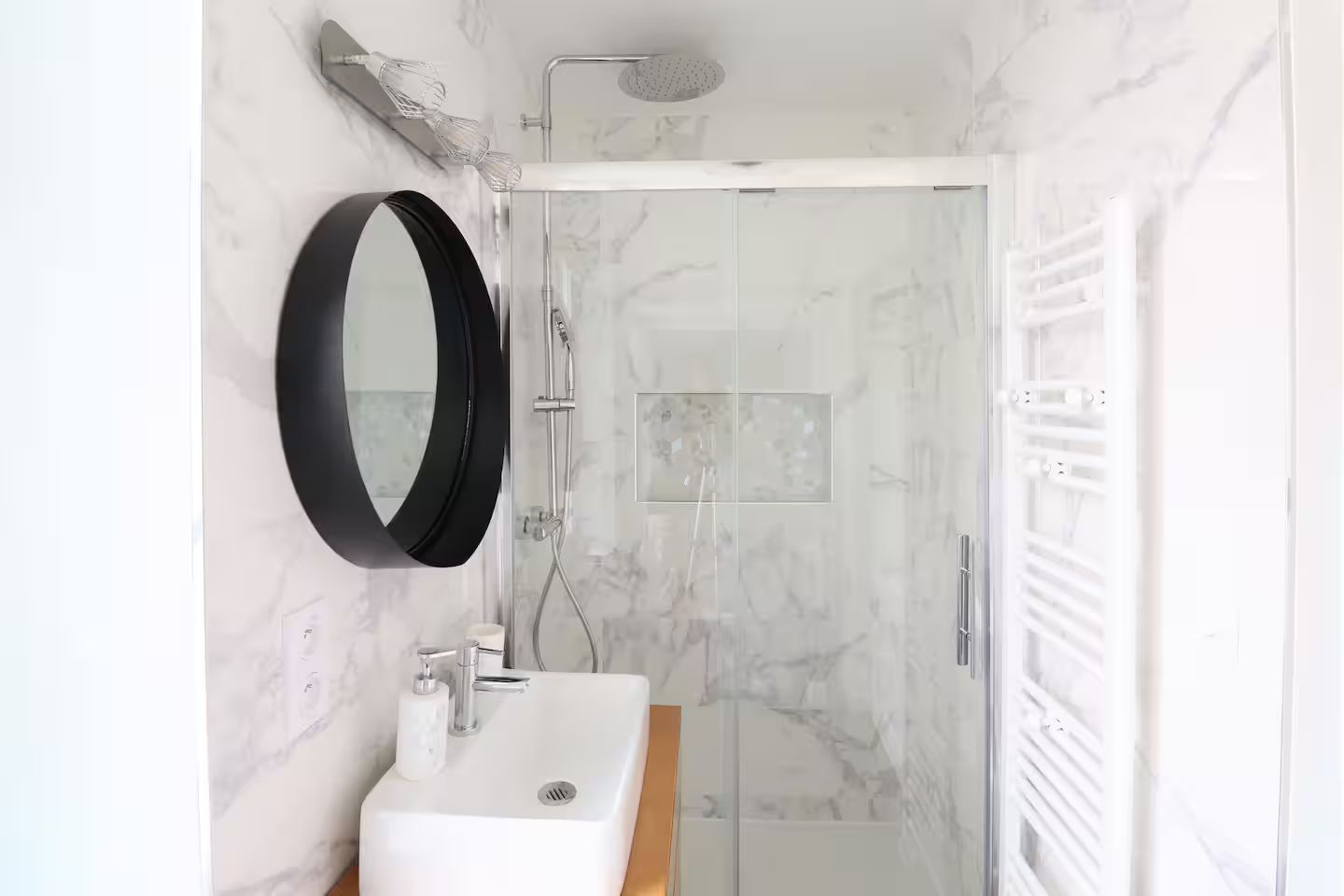 Une salle de bain avec lavabo, miroir et douche.