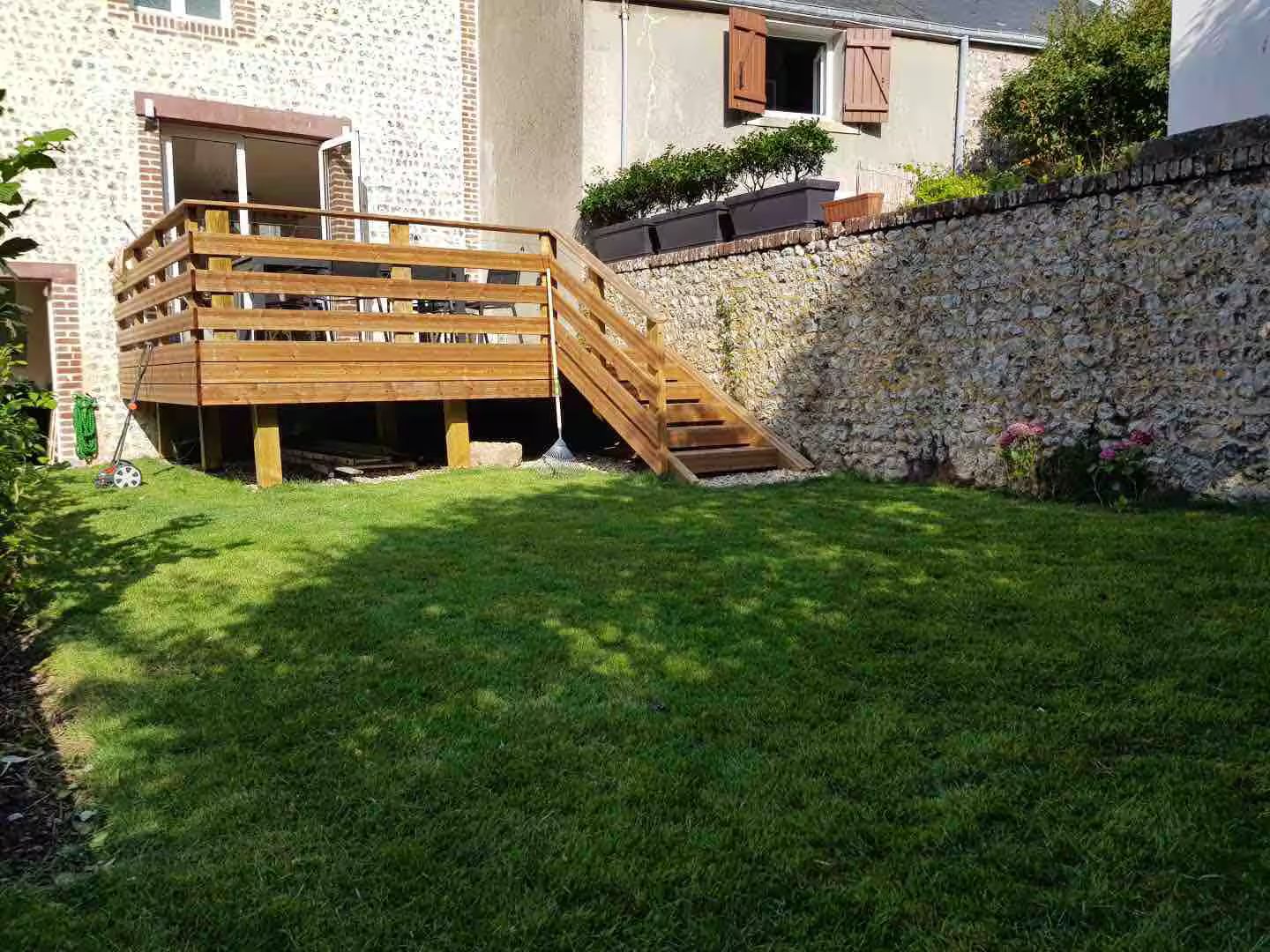 Une terrasse en bois avec des escaliers qui y mènent se trouve dans l'arrière-cour d'une maison.