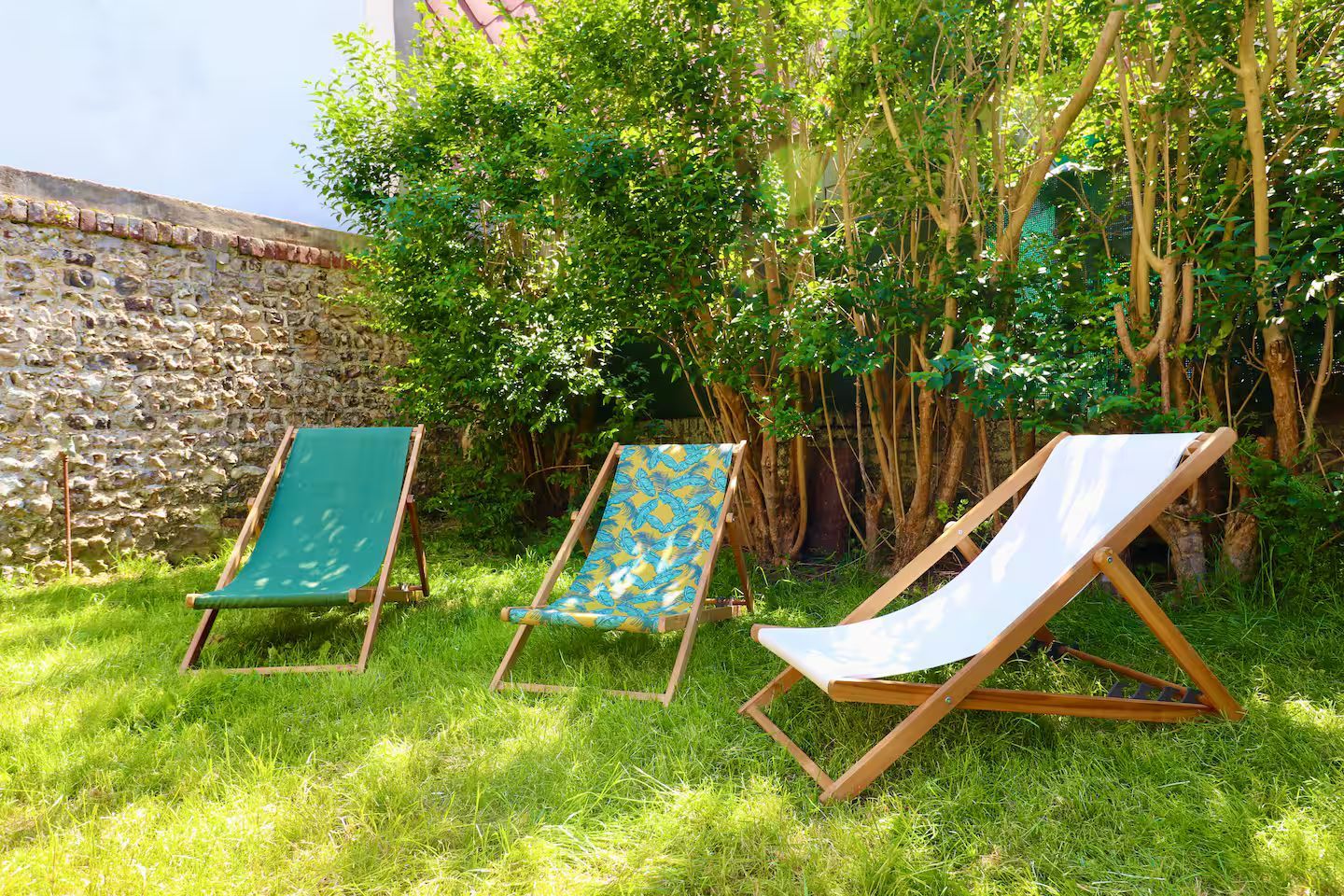 Trois chaises de jardin sont assises dans l'herbe dans un jardin.