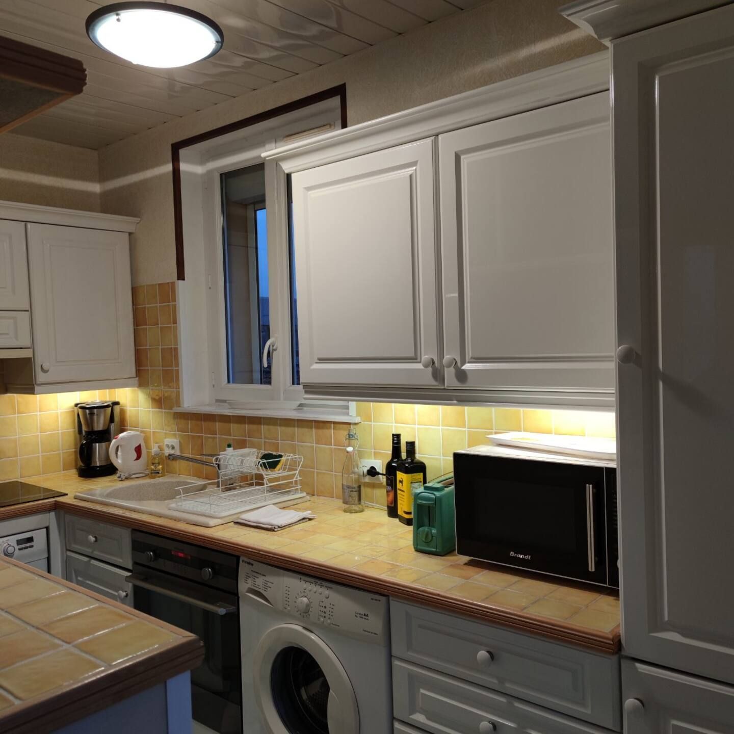 Une cuisine avec des armoires blanches et une machine à laver