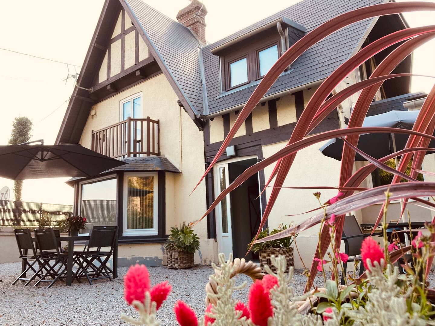 Une grande maison avec un balcon et des fleurs devant.