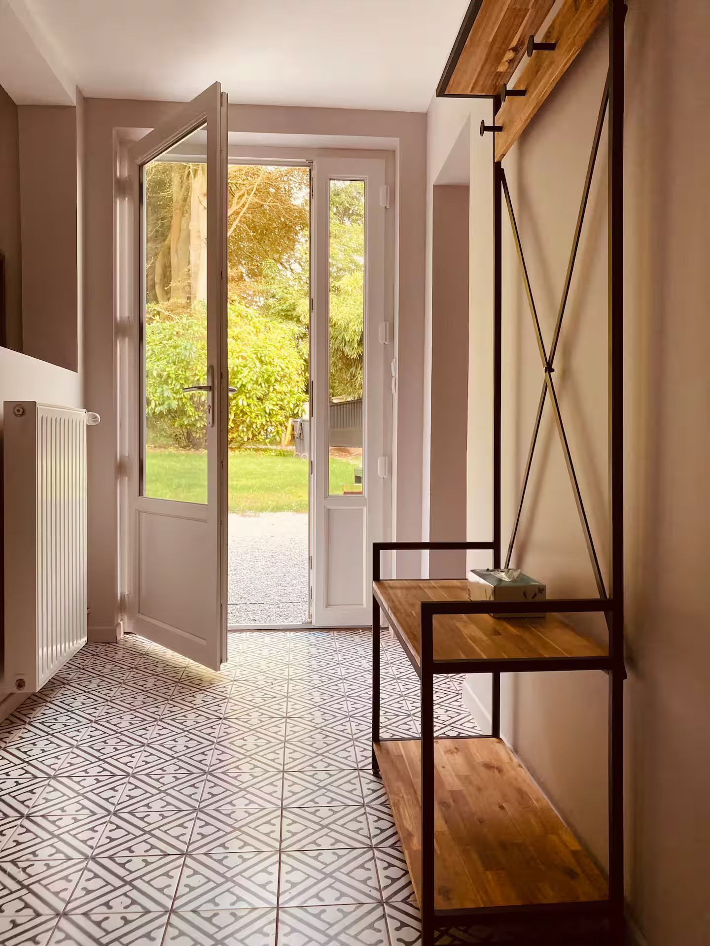 Un couloir avec un banc et une étagère devant une porte.