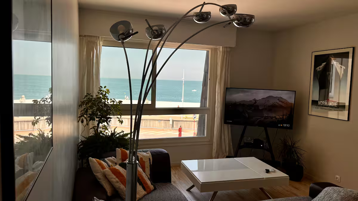 Un salon avec un canapé, une table, une télévision et une vue sur l'océan.