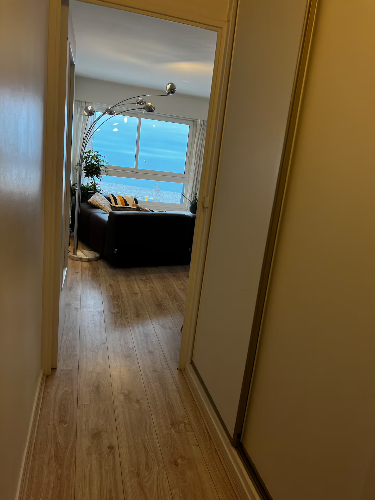 Un couloir menant à un salon avec un canapé et une lampe.