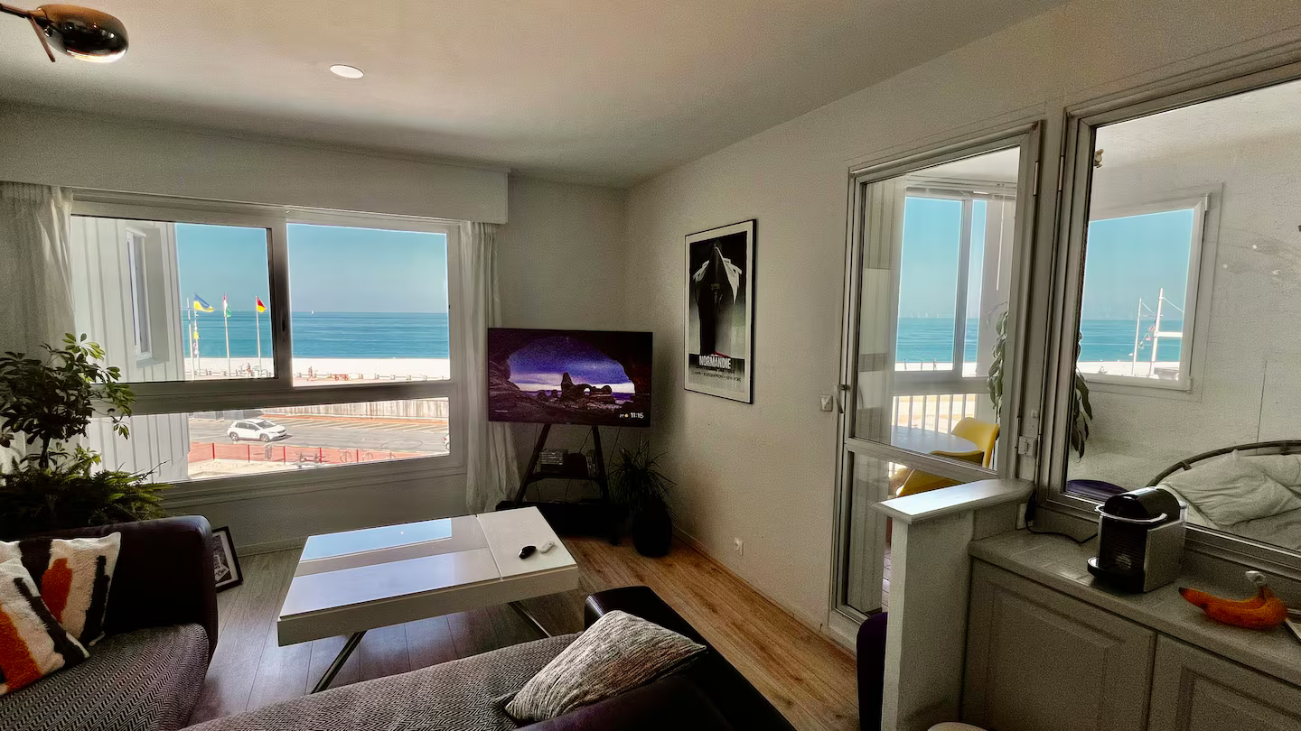 Un salon avec un canapé, une table, une télévision et une vue sur l'océan.