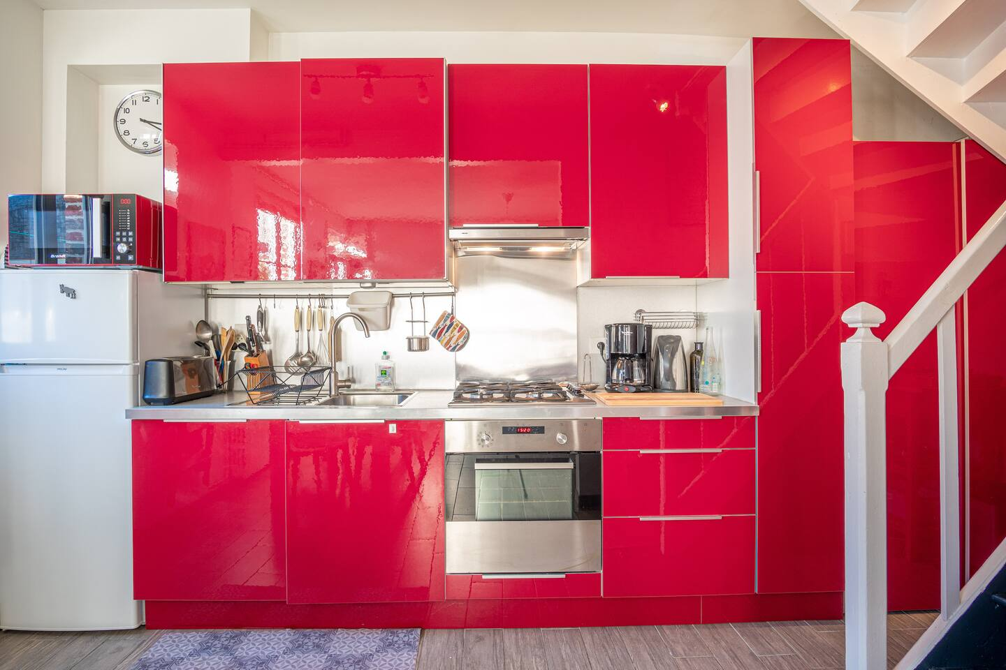 Une cuisine avec des armoires rouges et un réfrigérateur blanc