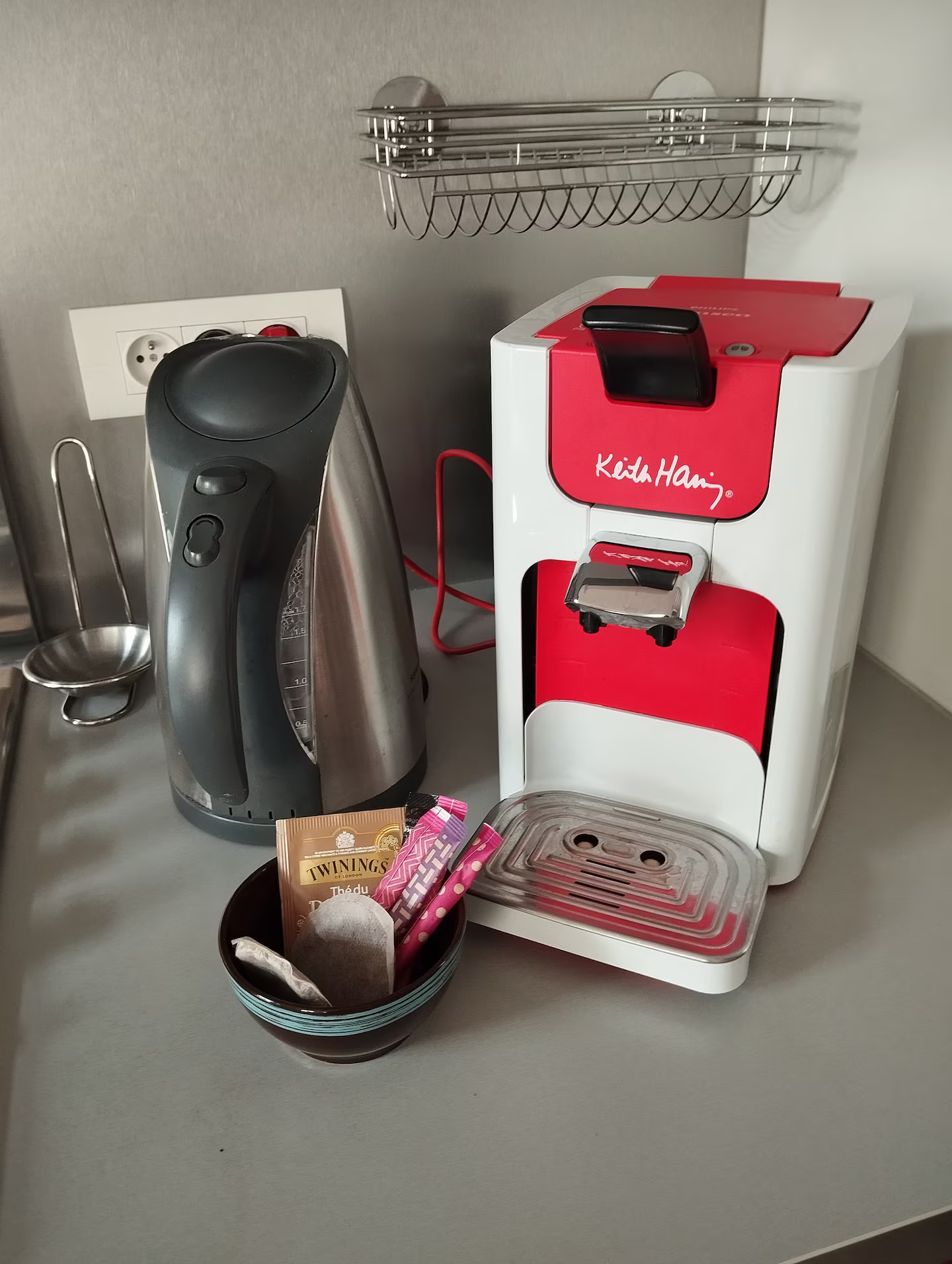 Une cafetière rouge et blanche est posée sur un comptoir à côté d'une bouilloire.