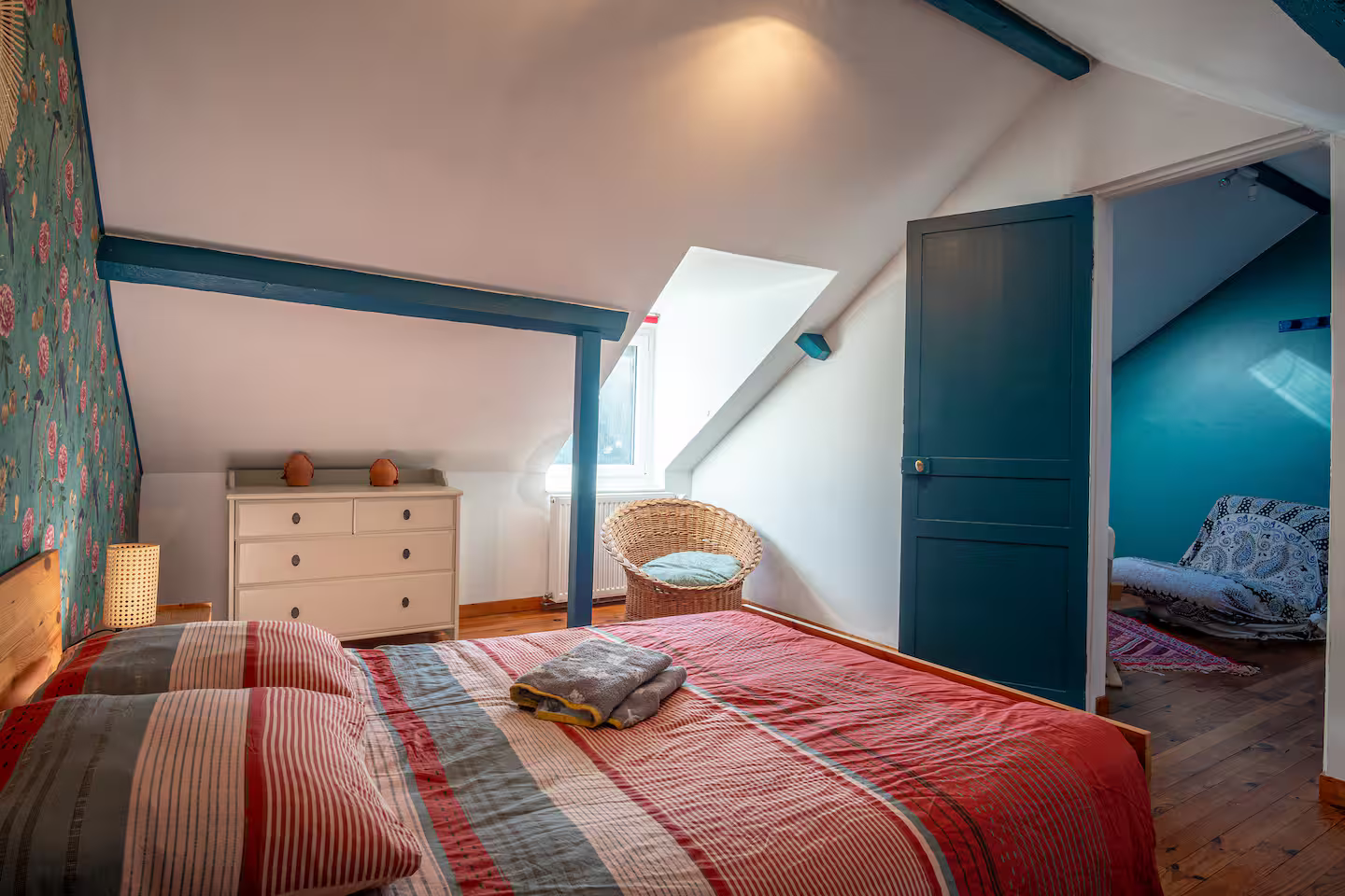 Une chambre avec un lit, une commode, une chaise et une fenêtre.