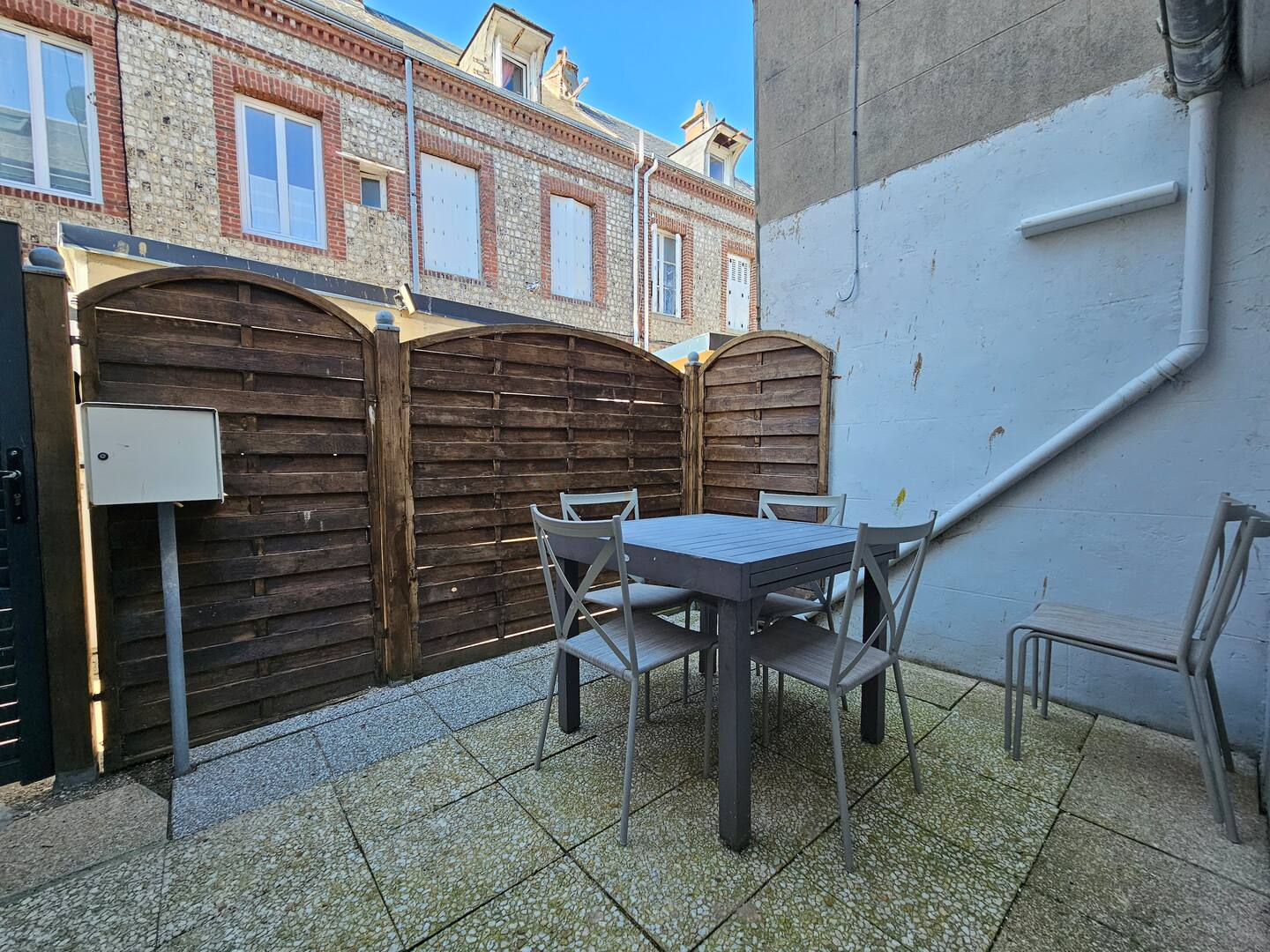 Un patio avec une table et des chaises devant un bâtiment.