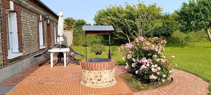 Une terrasse en briques avec un puits à souhaits et un rosier à côté d'un bâtiment en briques.
