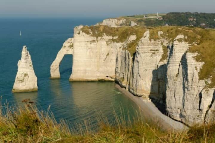 Falaises d'Étretat, France. Falaises de craie blanche avec arches naturelles et un piton rocheux, eau bleue.