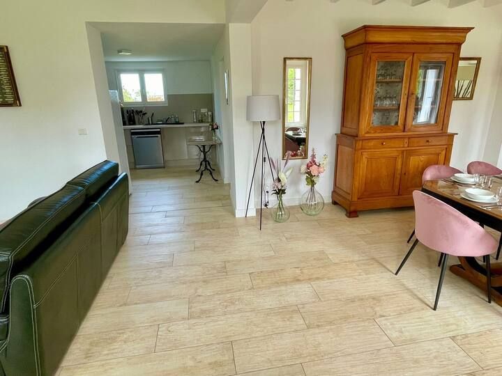 Espace de vie spacieux avec canapé vert, armoire en bois, table à manger et cuisine ouverte en arrière-plan.