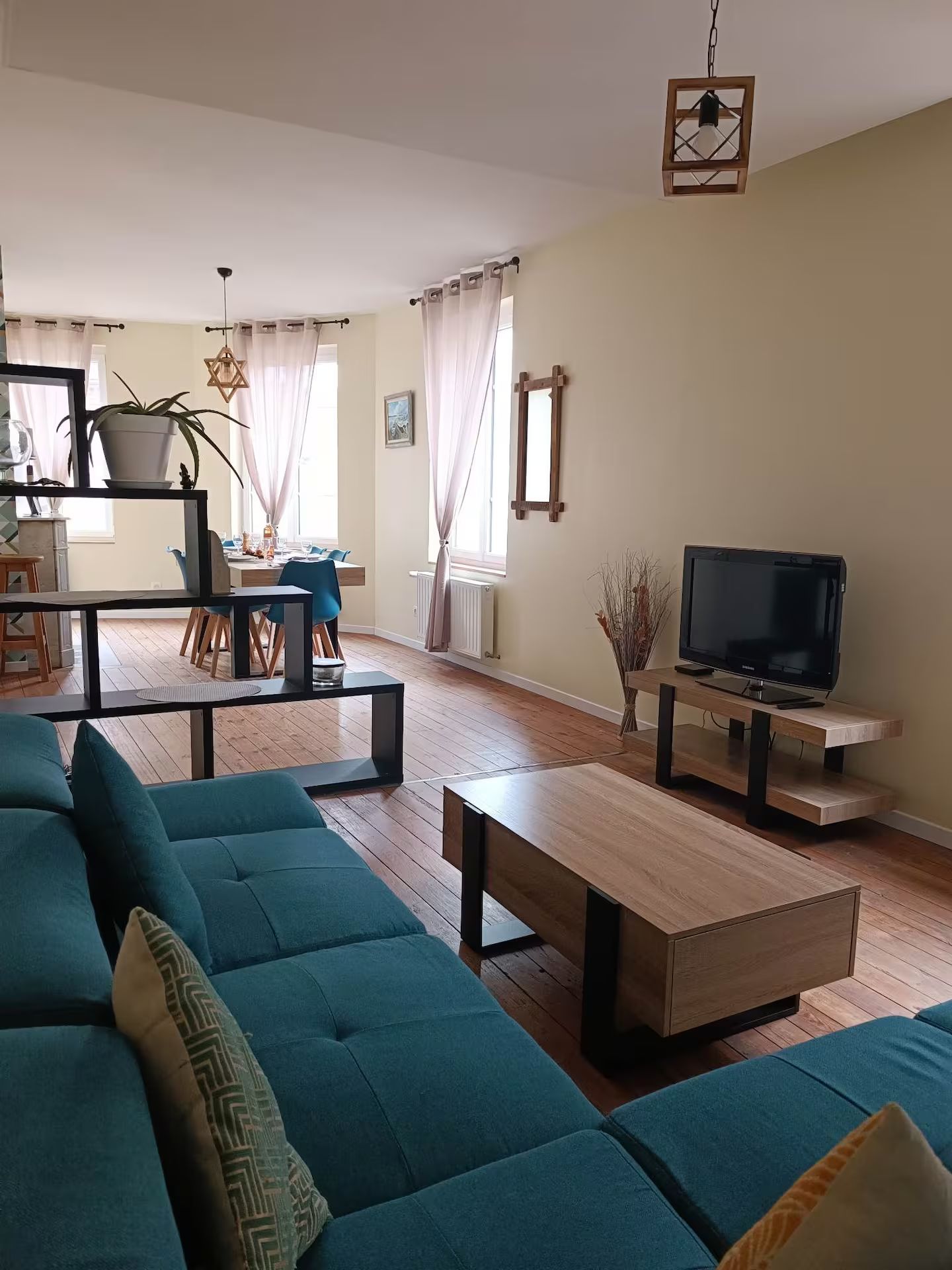 Un salon avec un canapé bleu, une table basse et une télévision.