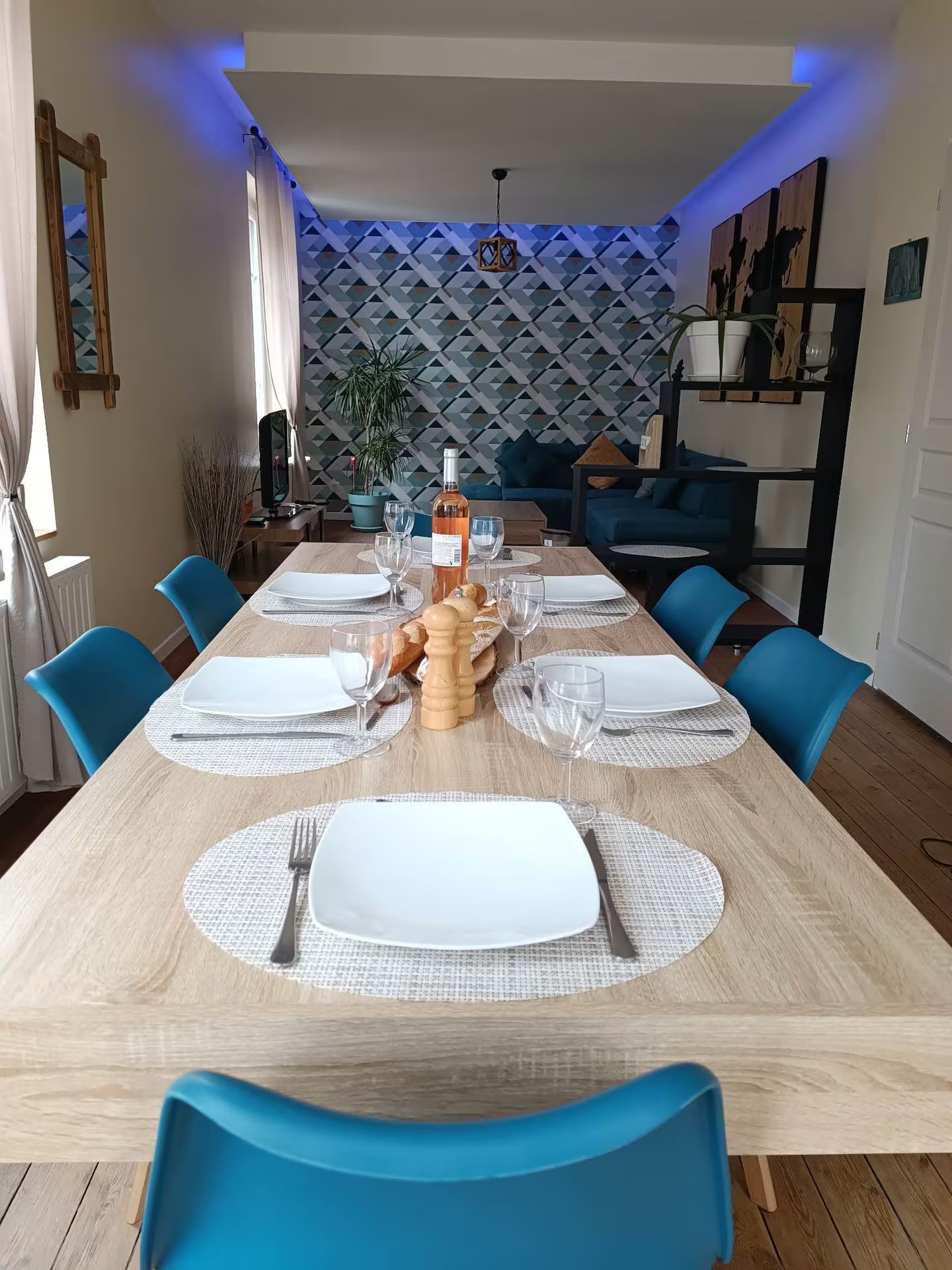 Une longue table à manger en bois avec des chaises bleues dans un salon.