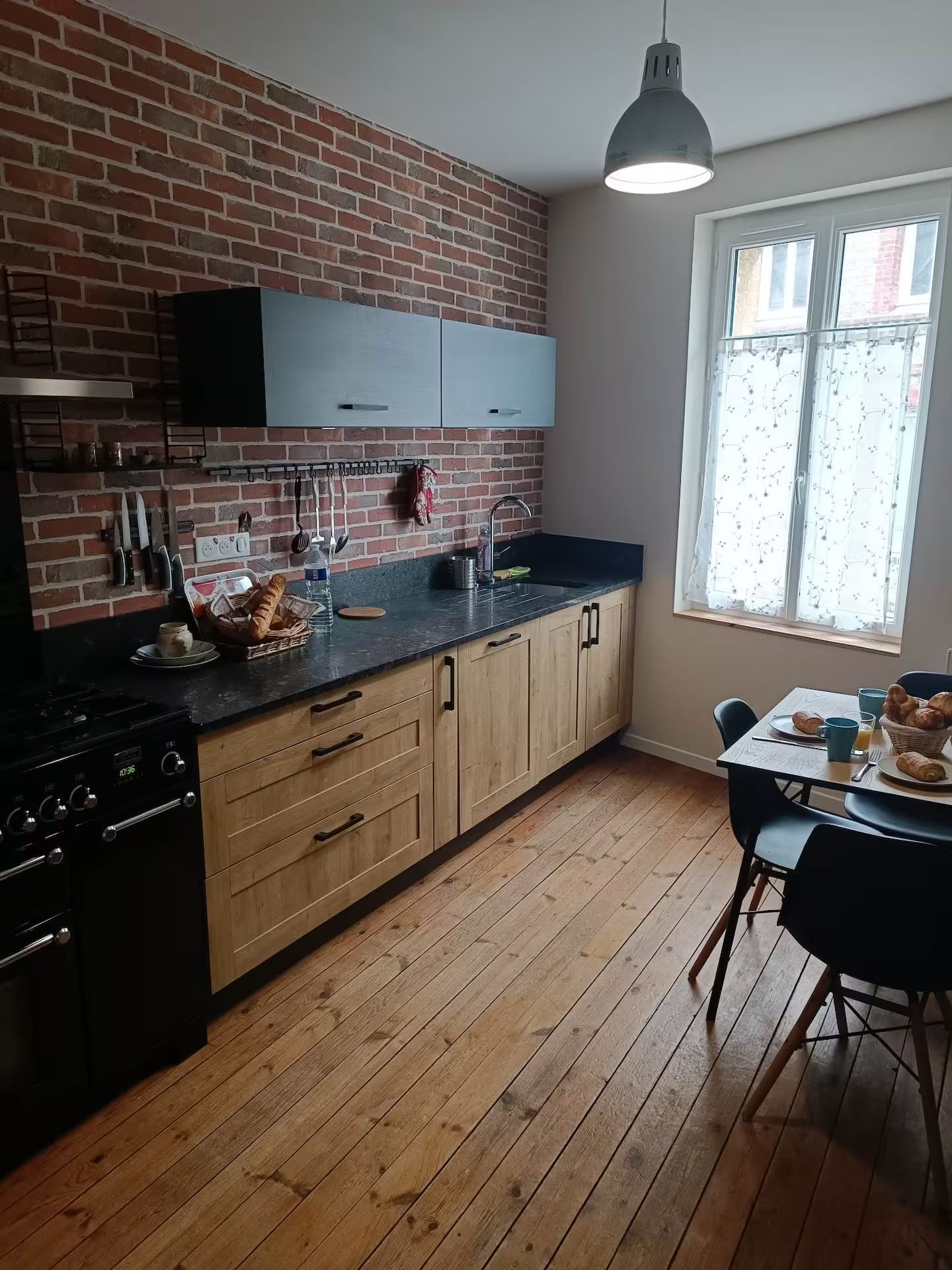 Une cuisine avec une table et des chaises et un mur de briques.