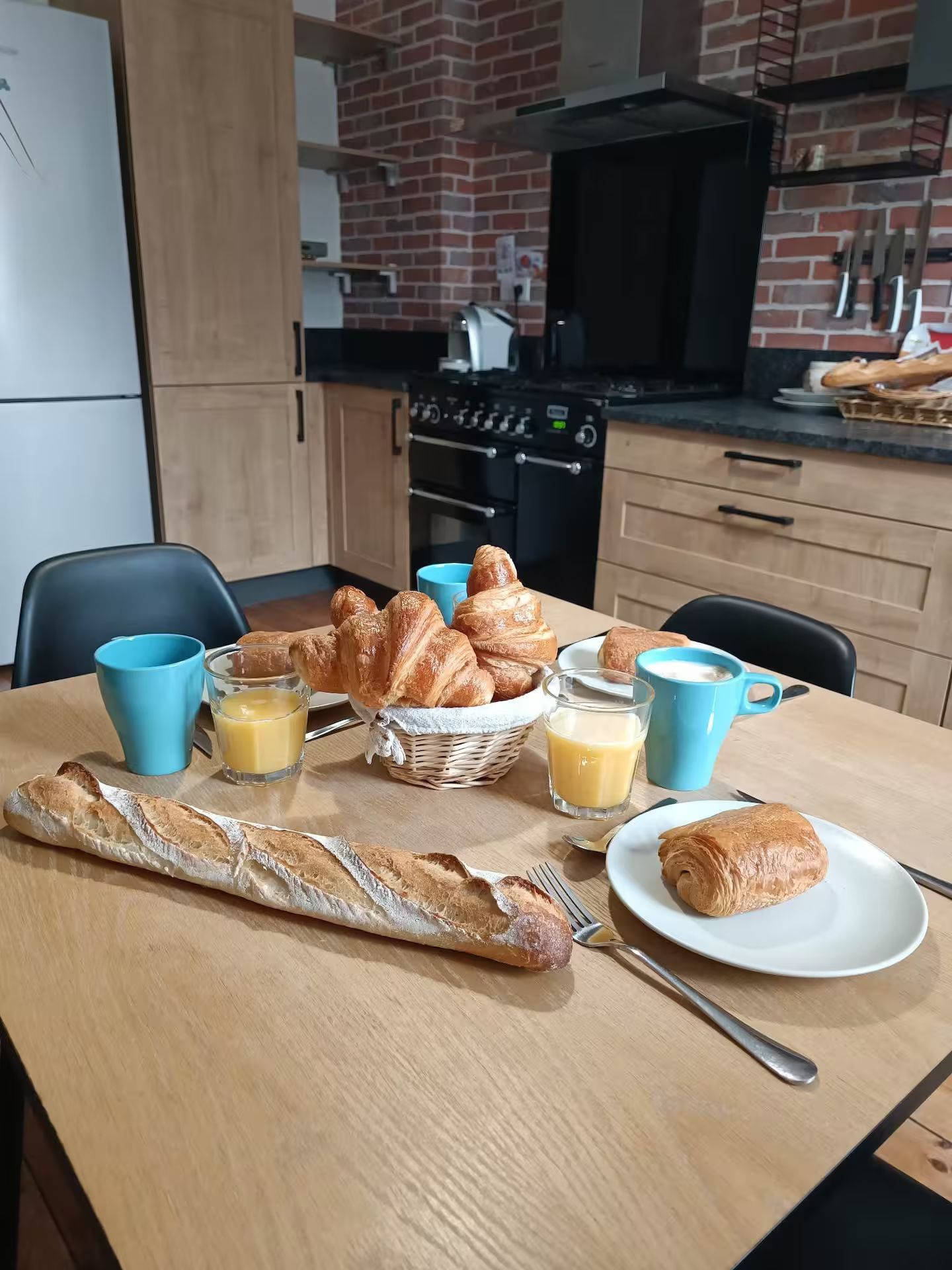 Une table en bois surmontée d'assiettes de nourriture et de boissons dans une cuisine.