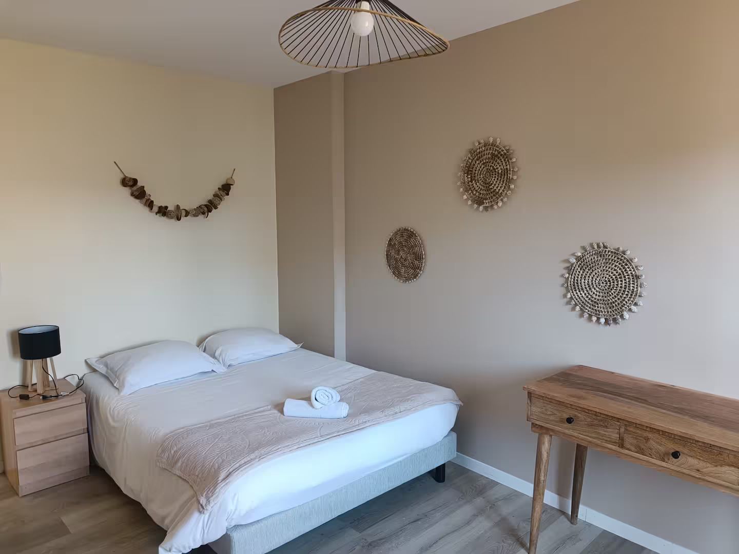 Une chambre avec un lit, une table de chevet, une table et une lampe.