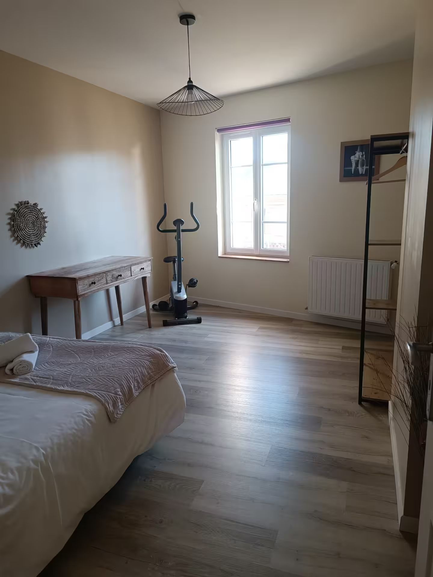 Une chambre avec un lit, un bureau, un vélo d'appartement et un miroir.