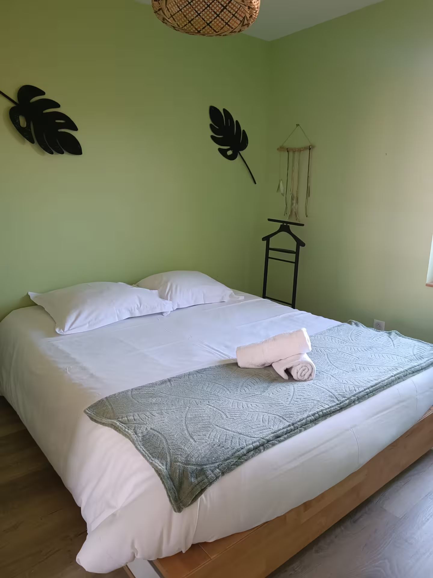 Un lit avec des draps et des oreillers blancs dans une chambre aux murs verts.