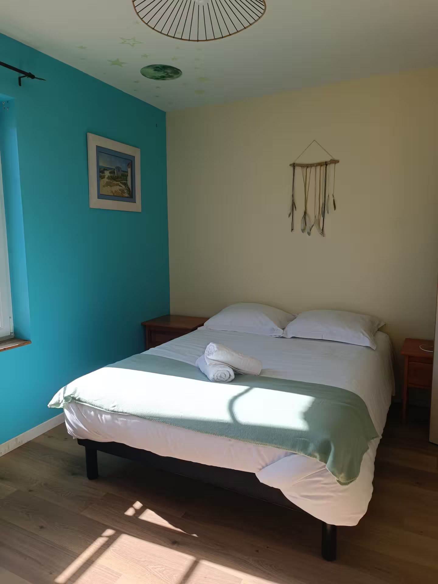 Une chambre avec un lit, deux tables de nuit et un mur bleu.