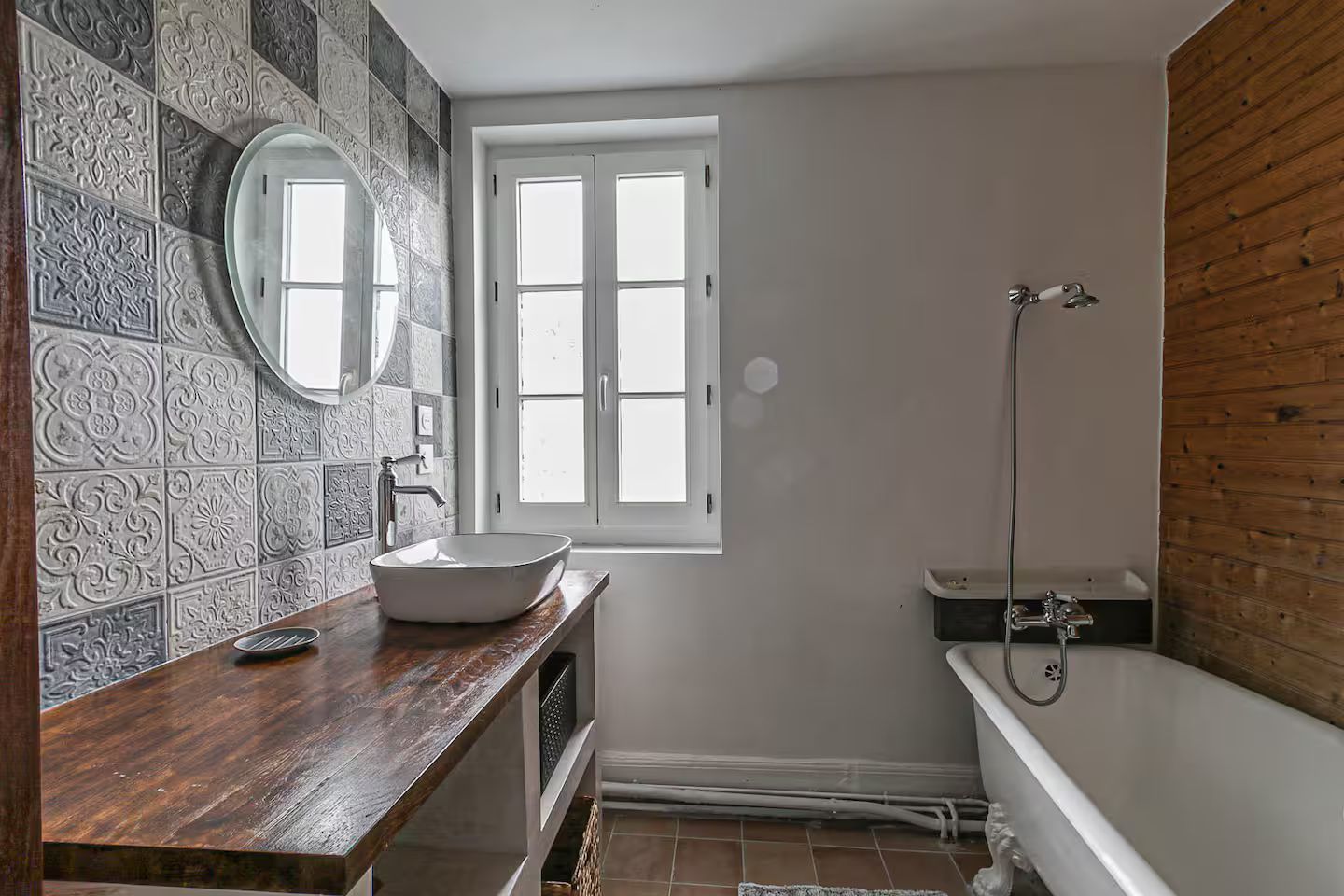 Une salle de bain avec baignoire, lavabo, miroir et fenêtre.