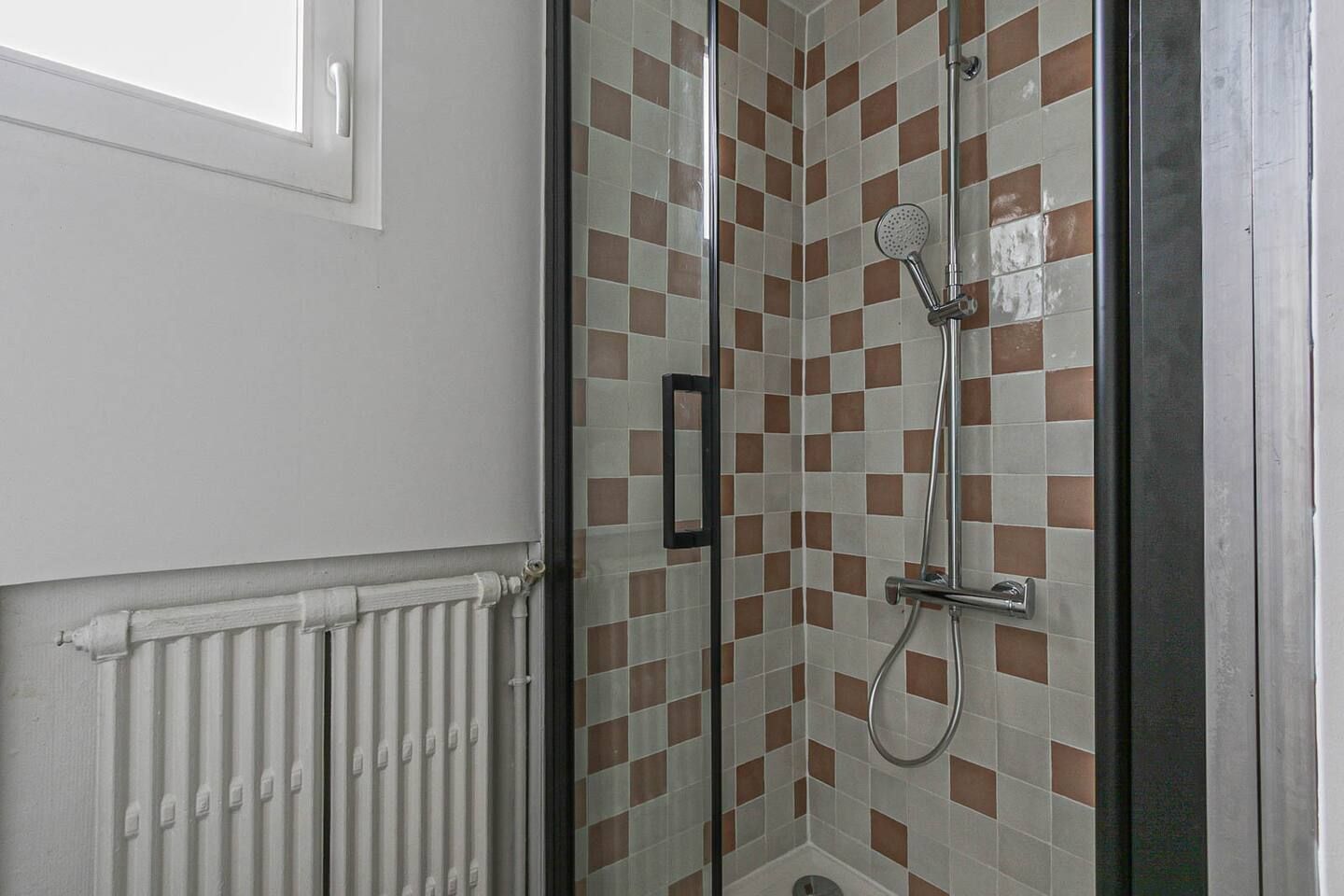 Une salle de bain avec une cabine de douche et un radiateur.