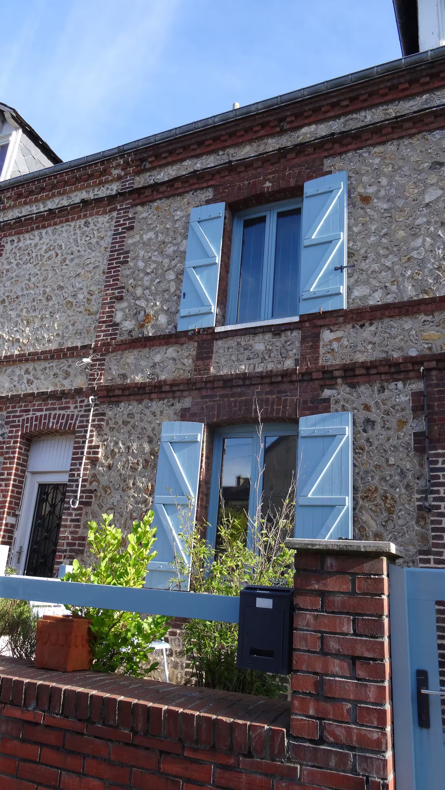 Un bâtiment en briques avec des volets bleus aux fenêtres