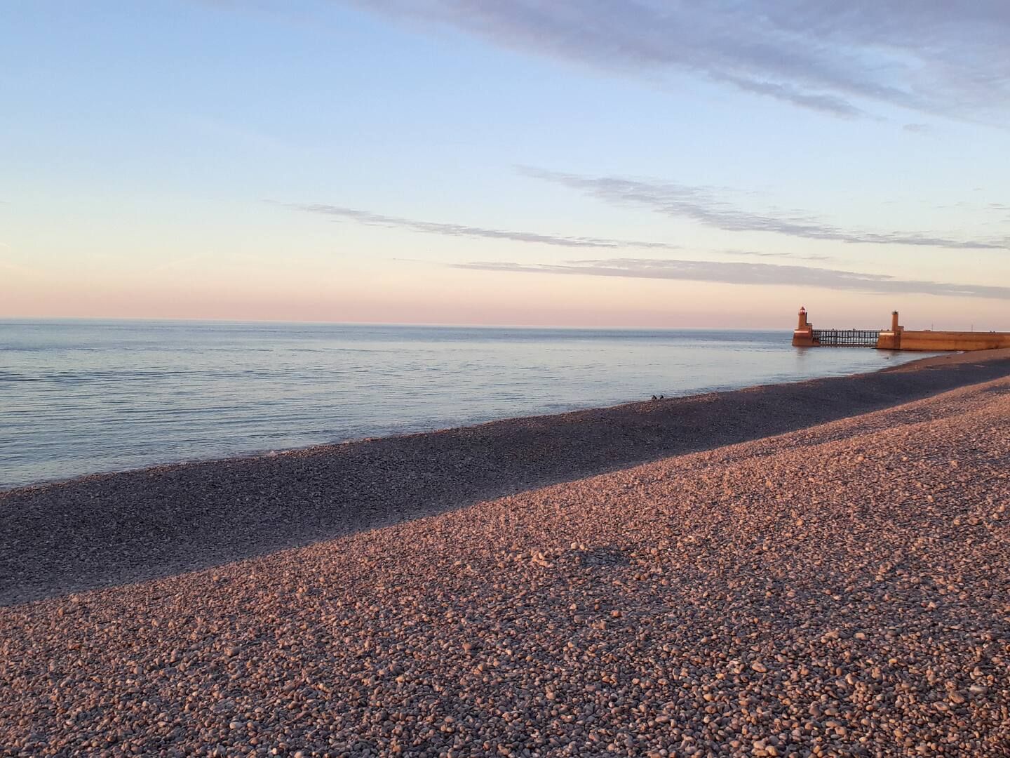 Une plage avec un phare au loin