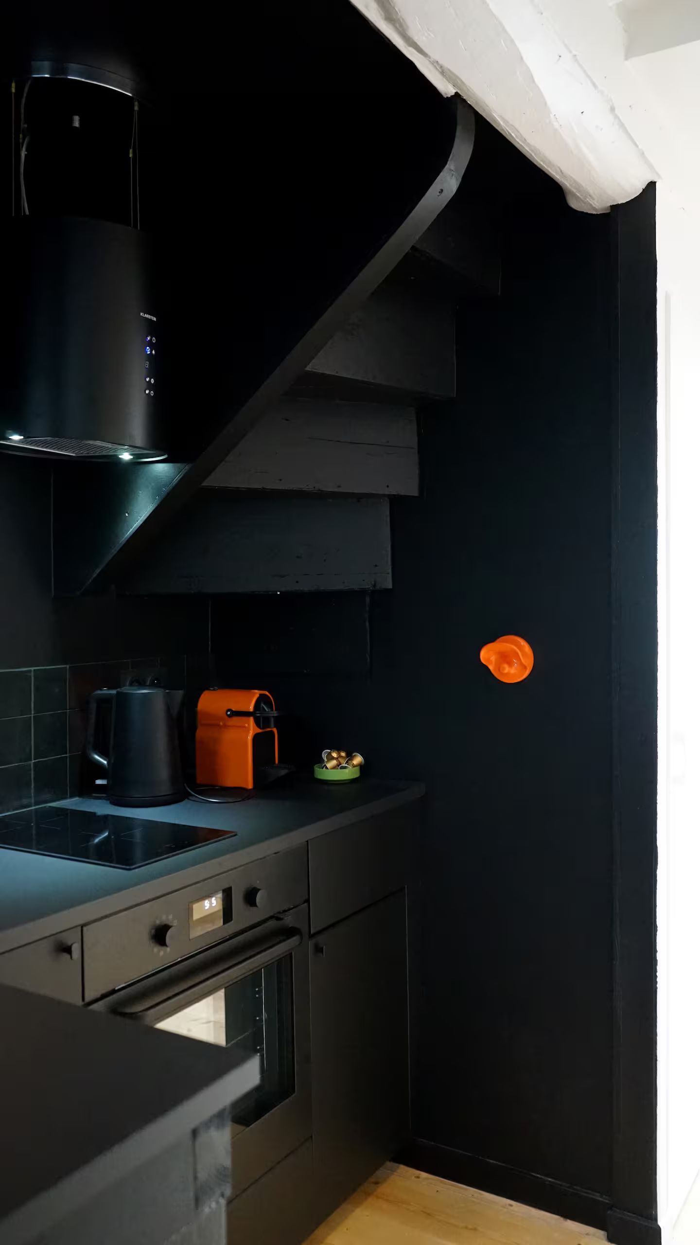 Une cuisine avec des armoires noires et un escalier noir