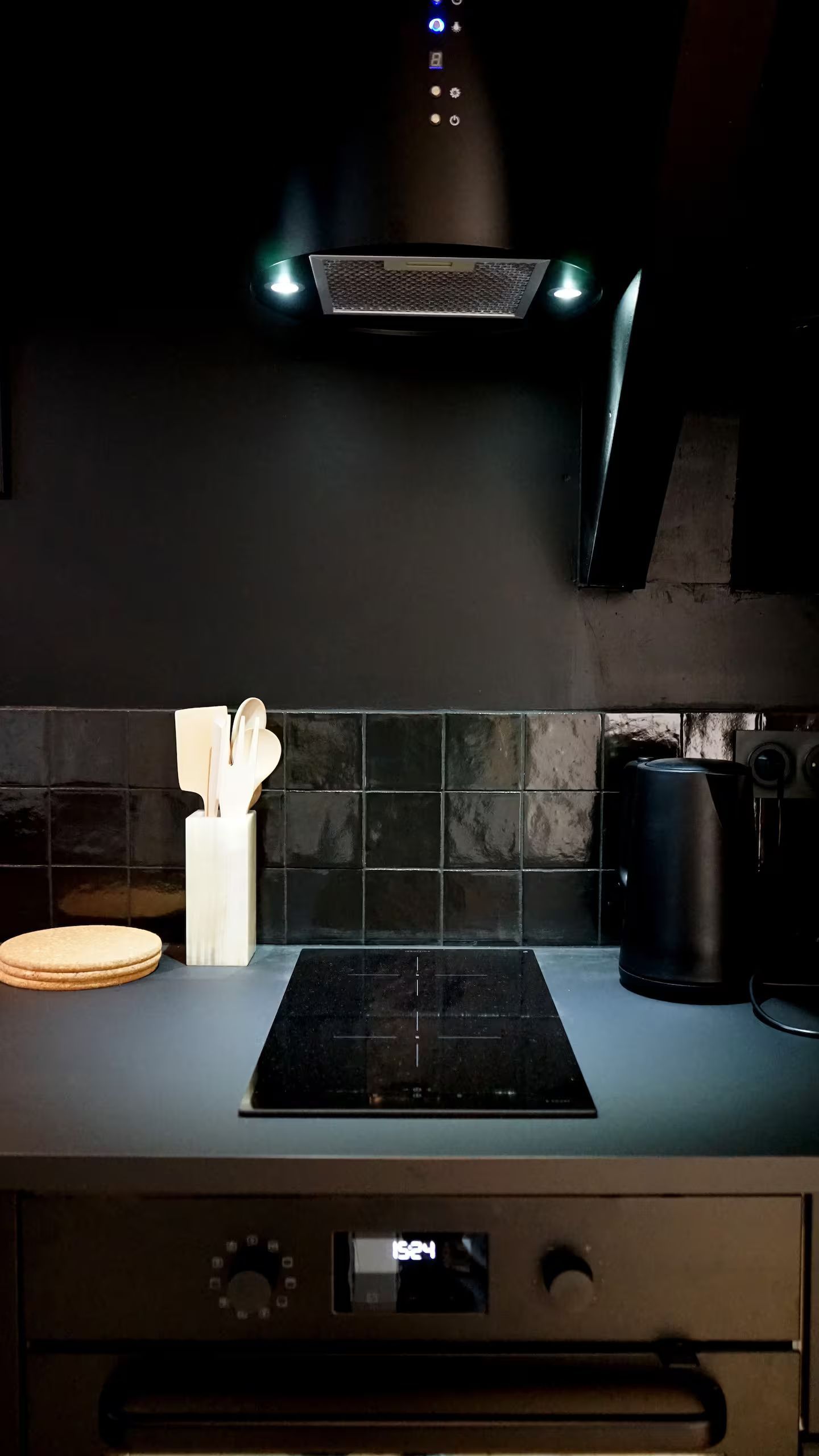 Une cuisine avec une cuisinière noire et une hotte noire.