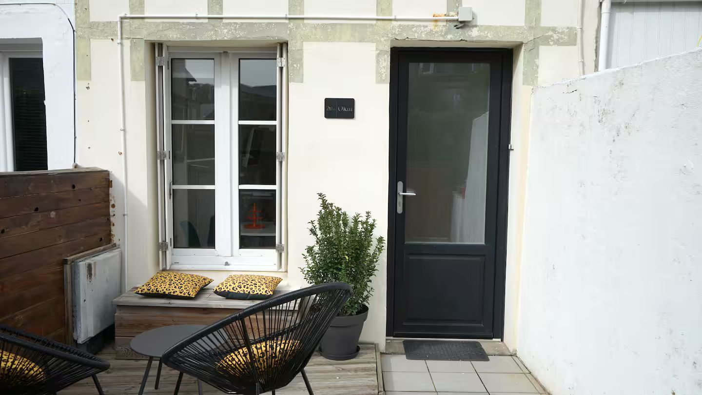 Un petit patio avec des chaises et une table devant une maison.