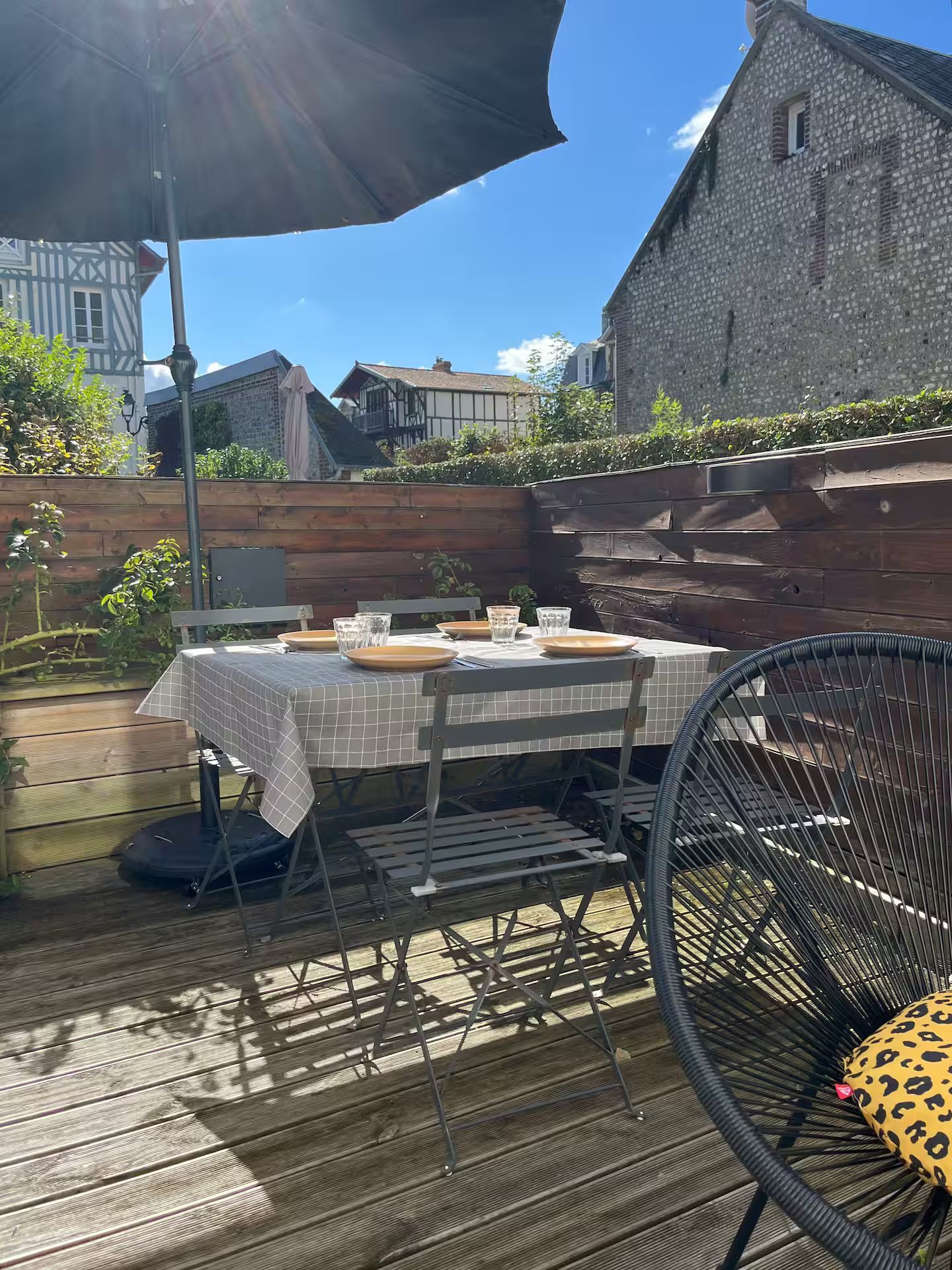 Une terrasse en bois avec une table et des chaises sous un parasol.