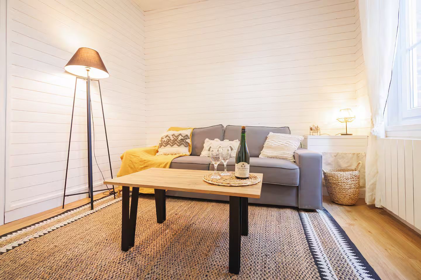 Un salon avec un canapé, une table basse, une lampe et un tapis.