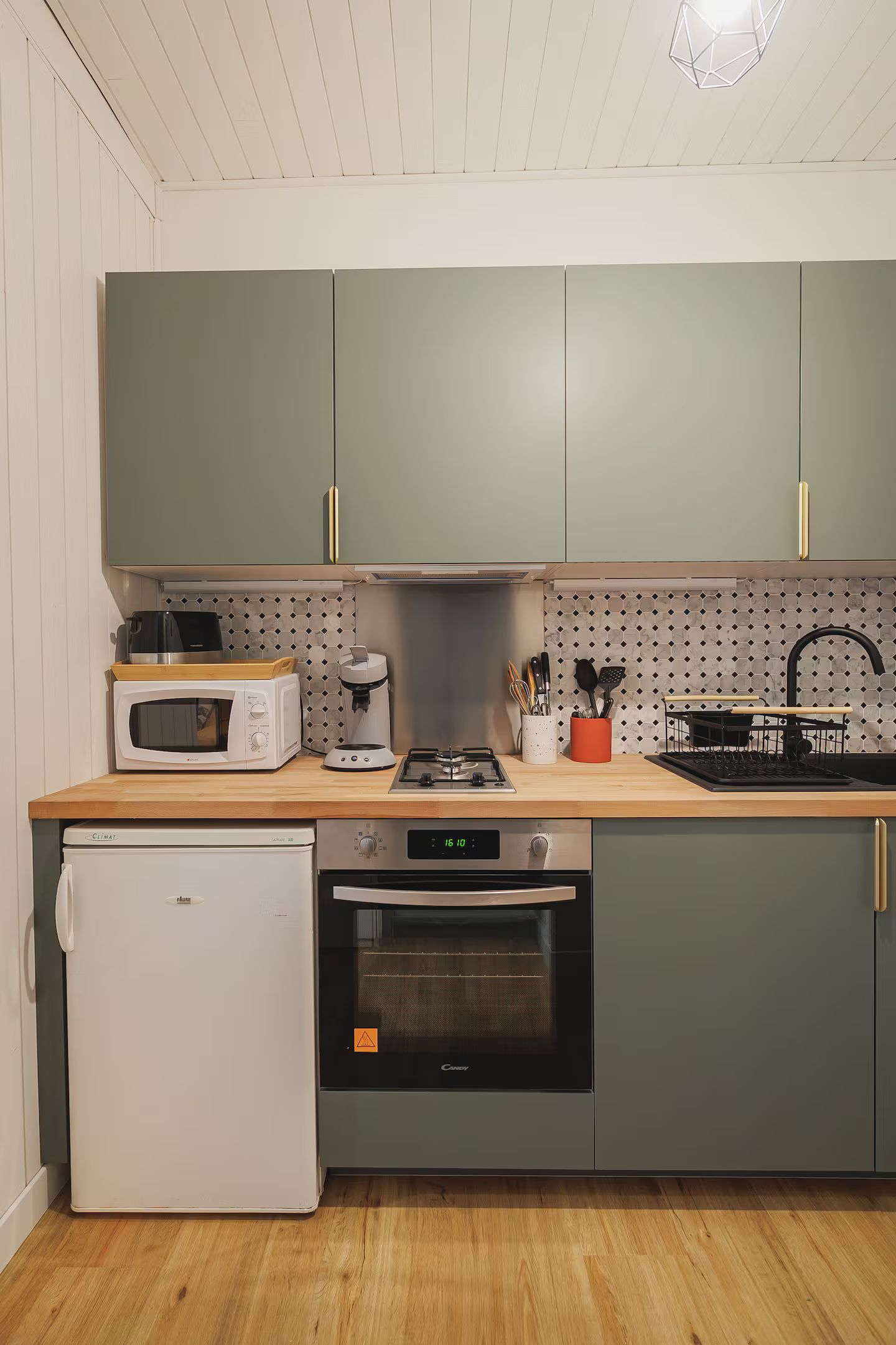 Une cuisine avec des armoires vertes et un réfrigérateur blanc.