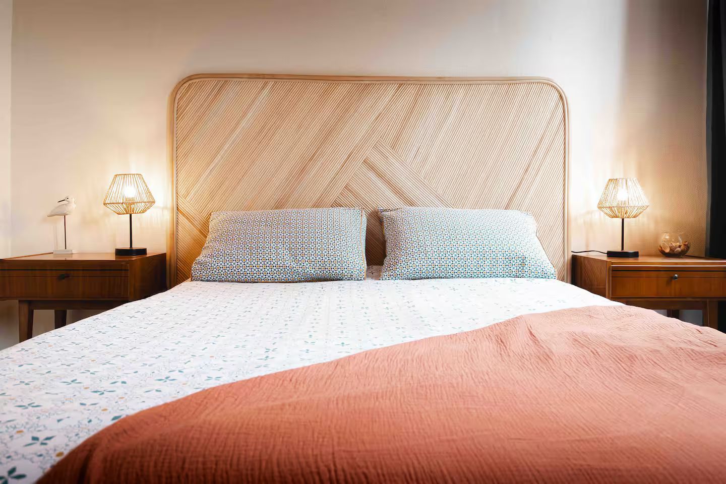 Un lit avec une tête de lit en osier et deux tables de nuit dans une chambre.