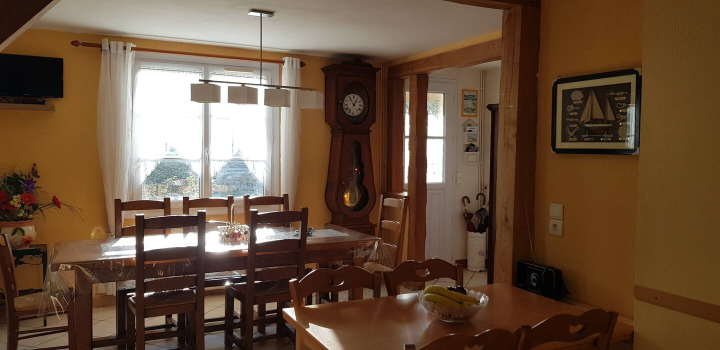 Une salle à manger avec une table et des chaises et une grande horloge.