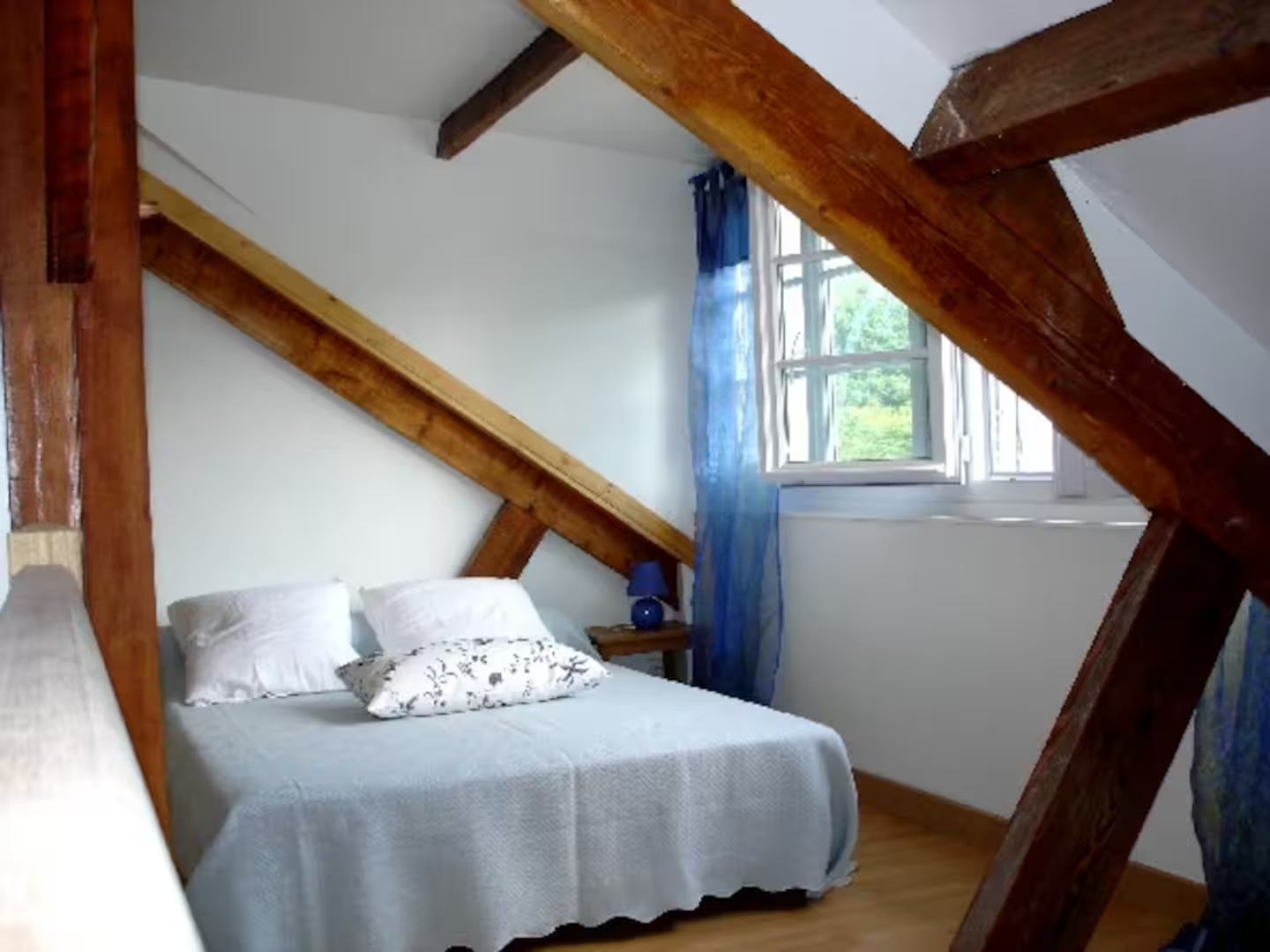 Une chambre avec un lit et une fenêtre avec des rideaux bleus