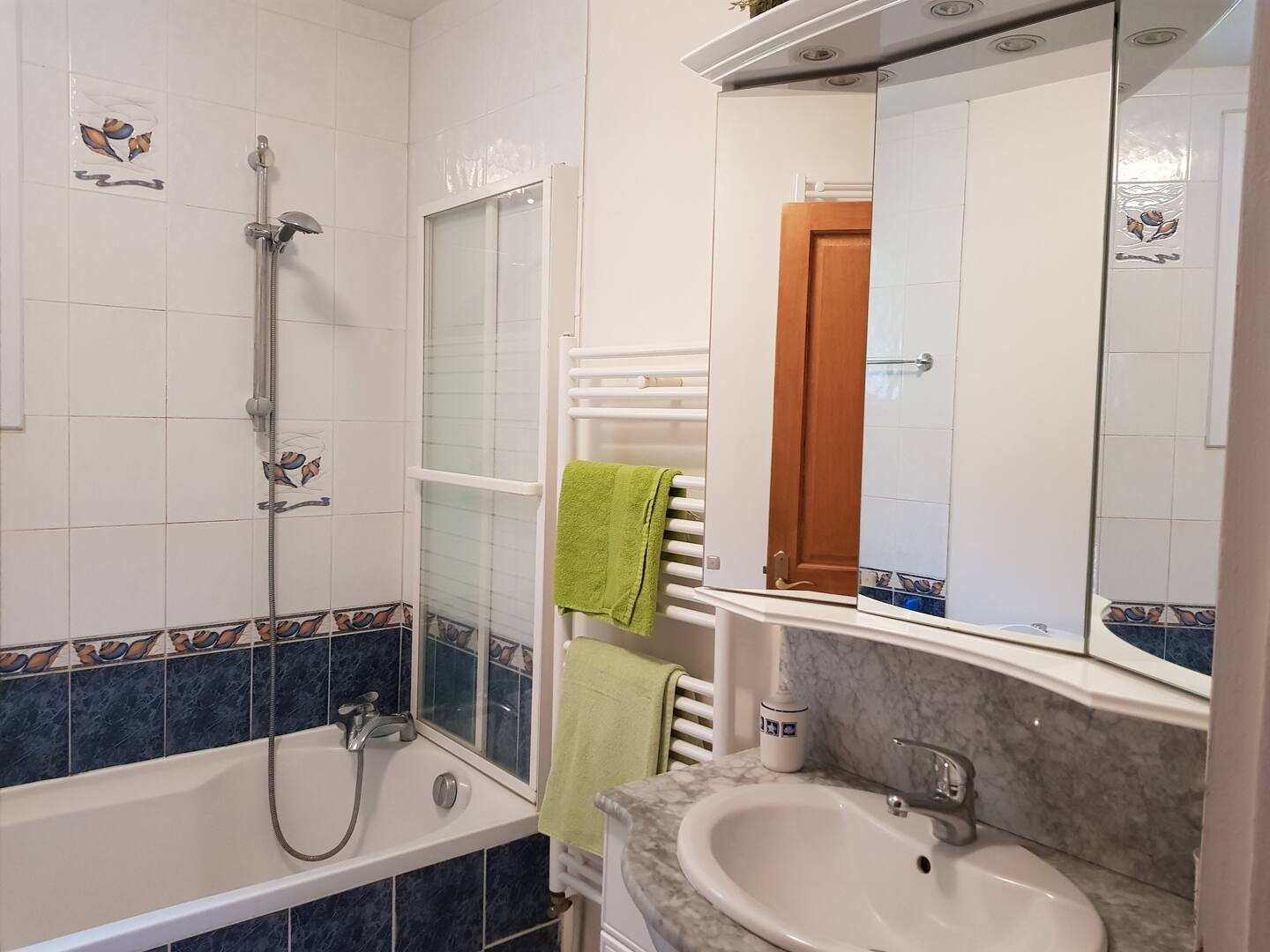 Une salle de bain avec baignoire, lavabo, miroir et porte-serviettes.