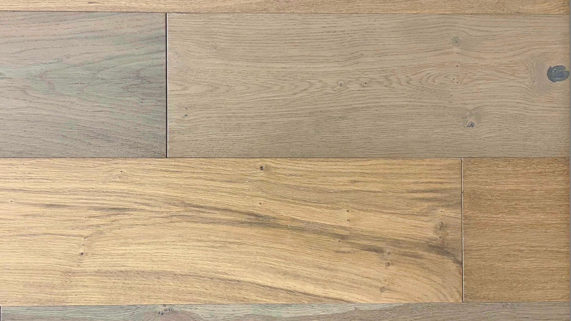 This image presents a selection of hardwood flooring options, highlighting the diverse range of colors and grain patterns available from a contractor in Athens, Georgia. The top half shows two lighter wood planks with subtle grain details, while the bottom half displays richer, more pronounced grain patterns on darker wood. The samples are placed adjacent to each other for direct comparison, showcasing the natural beauty and texture that could complement a variety of interior designs and preferences. This collection is likely part of a showcase for potential clients to select the perfect hardwood flooring for their homes.