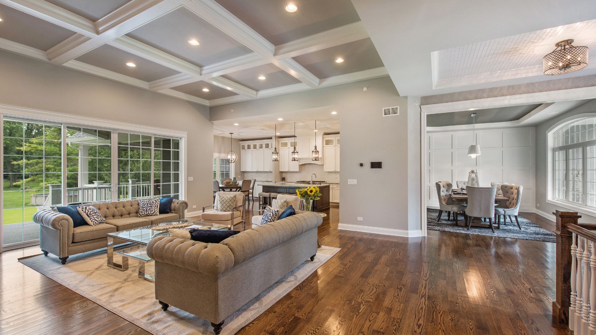 Elegant living room with dark hardwood floors, plush sofas, and a coffered ceiling.