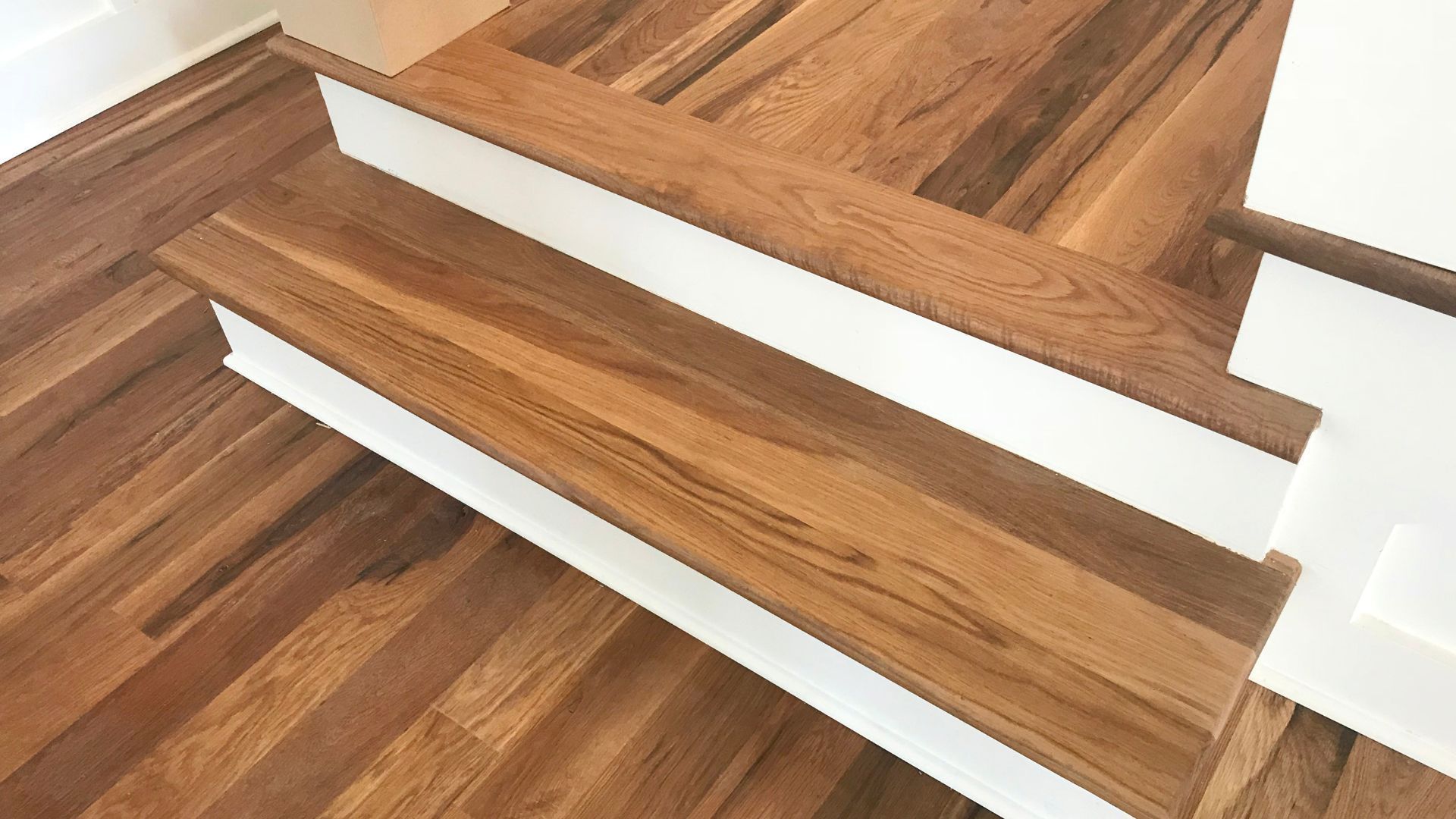 Warm-toned hardwood stairs with white risers matching the floor in Athens, GA.
