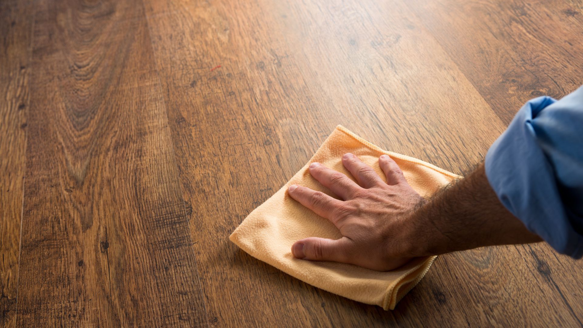 A person cleaning a wooden surface with a cloth in Athens, GA, emphasizing the wood grain.