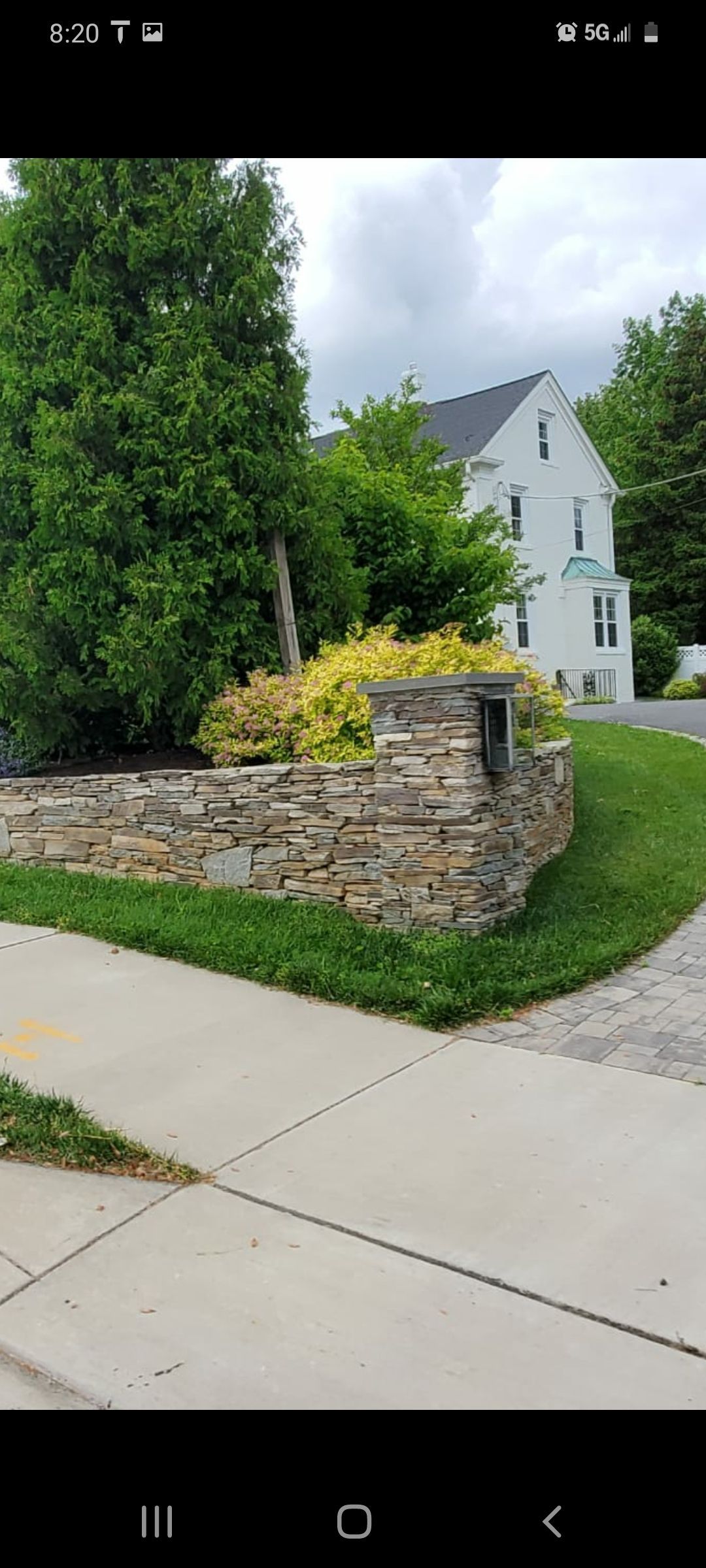 A white house with a stone wall in front of it