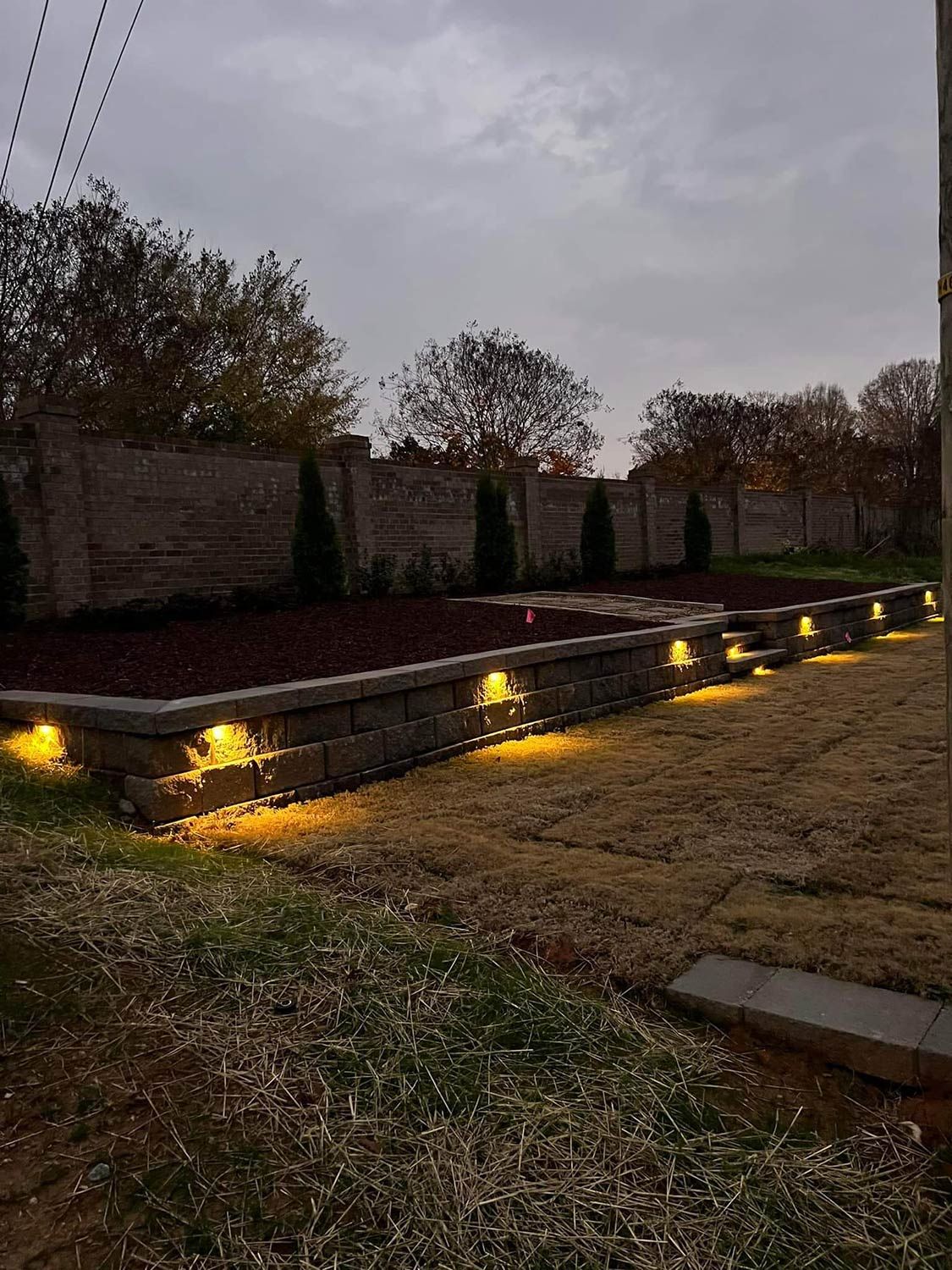 A brick wall with lights on it in a yard