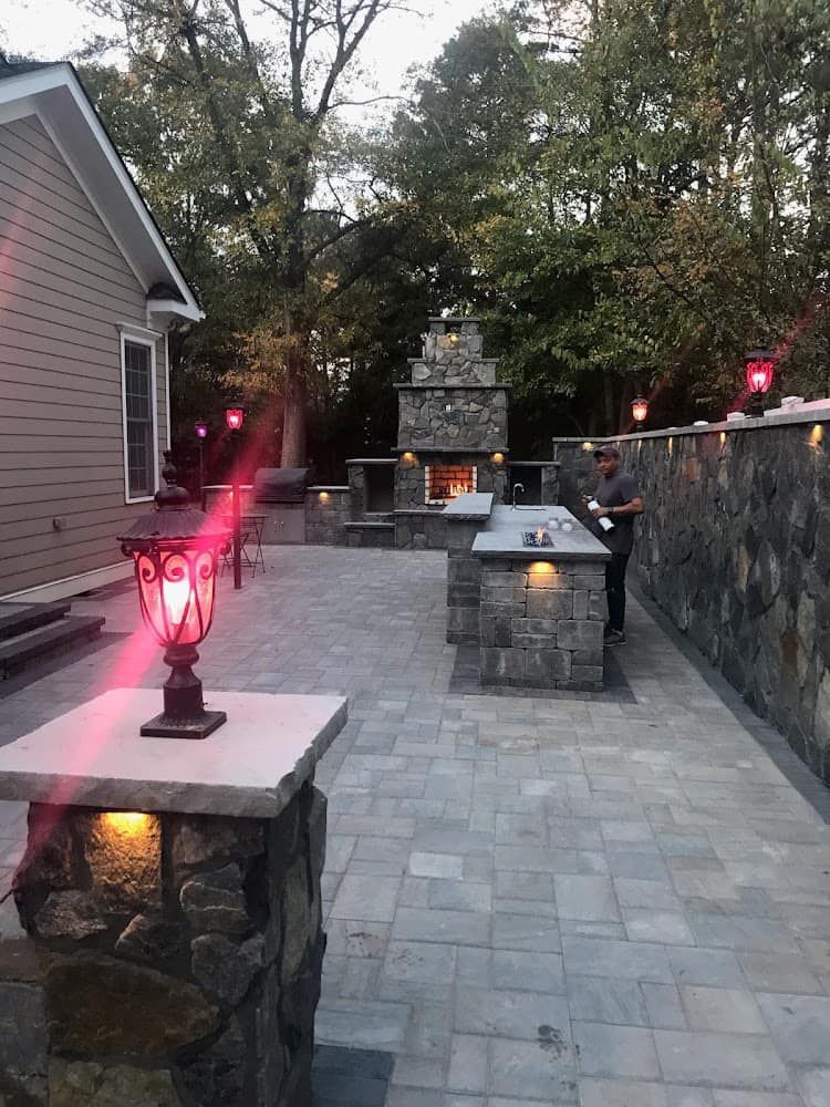 A man is standing in front of a fireplace on a patio