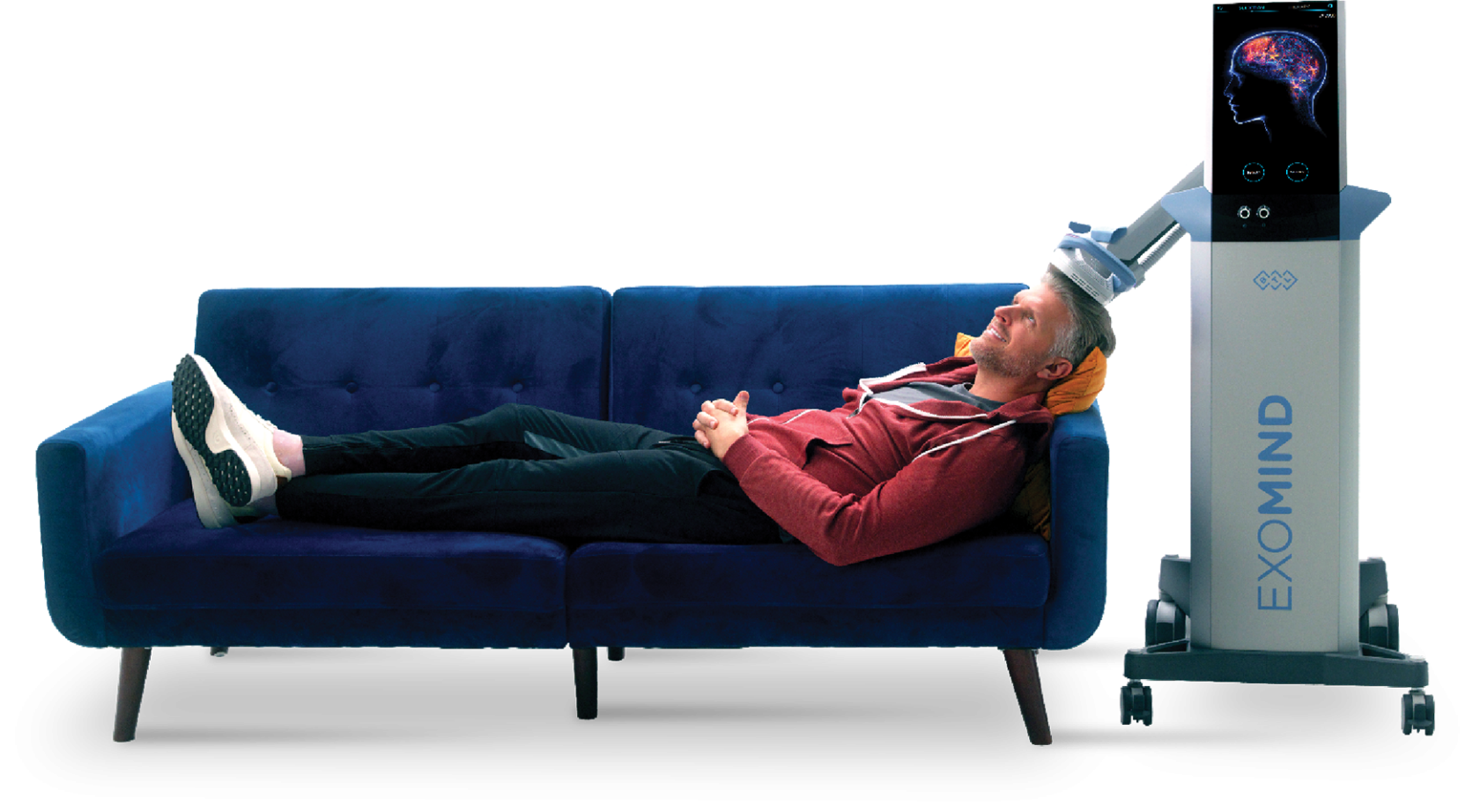 A man is laying on a blue couch next to a machine that says exomind.