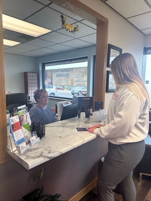 A woman is standing at a counter in an office talking to a man.
