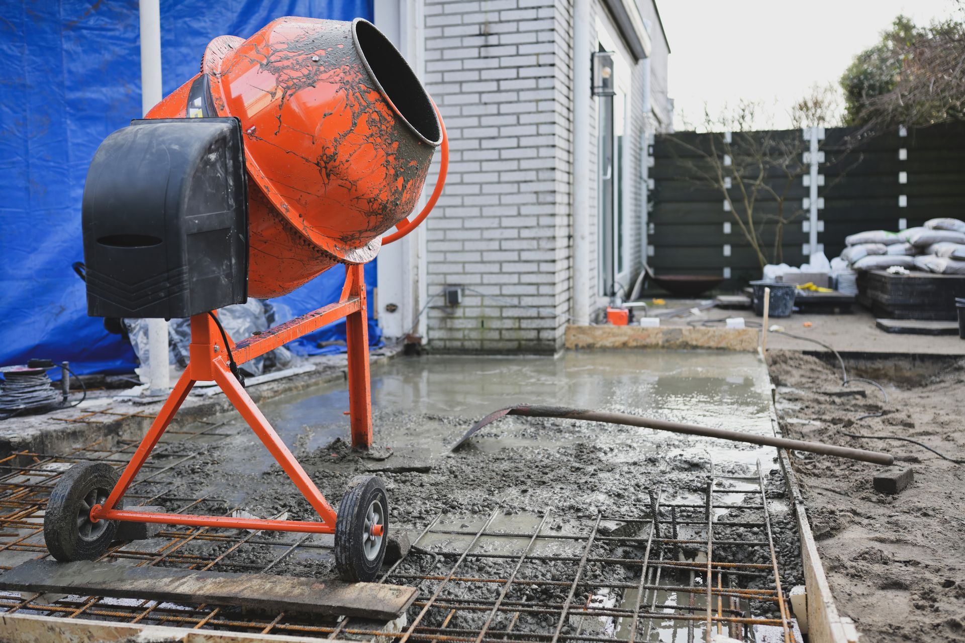 Orange concrete mixer on a residential patio site with freshly poured concrete and rebar Orange concrete mixer on a residential patio site with freshly poured concrete and rebar
